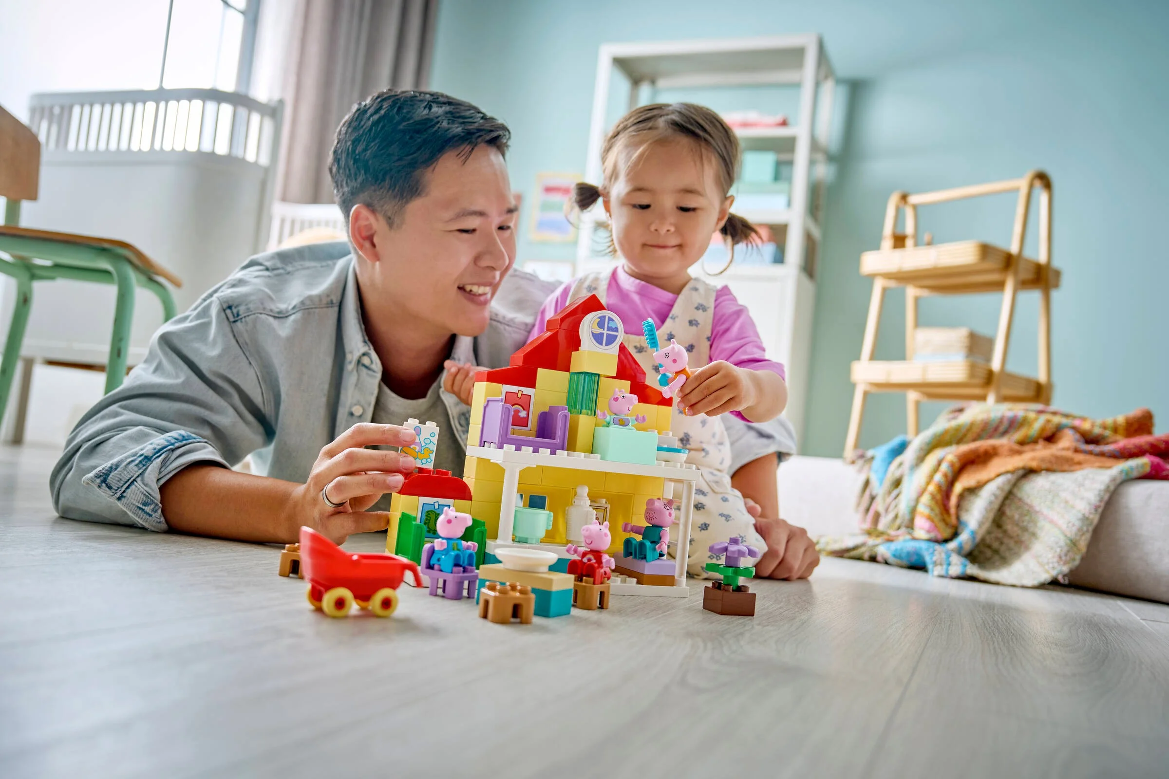 Un tată și fiica se joacă împreună cu casa LEGO DUPLO, zâmbind și construind.