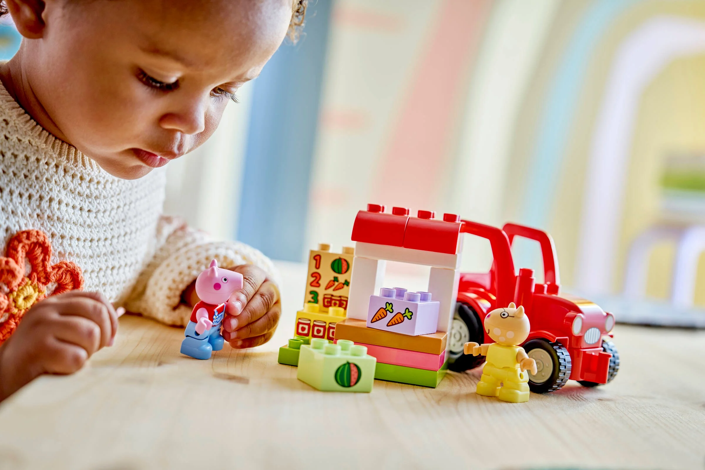 Copil se joacă cu tractorul și piața LEGO Duplo, explorând formele și culorile.