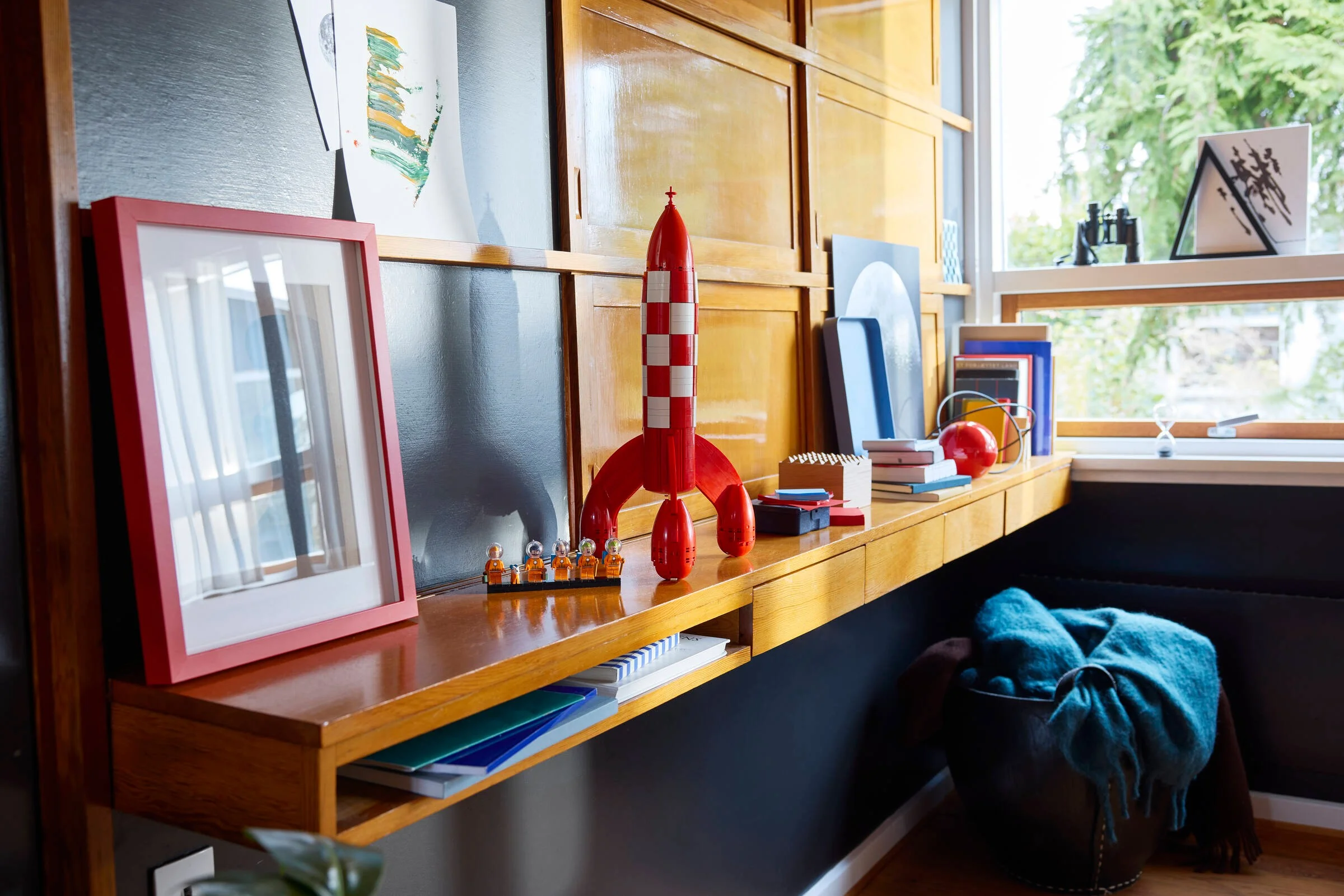 Modelul rachetei Tintin pe un raft din lemn, alături de minifigurinele personajelor.