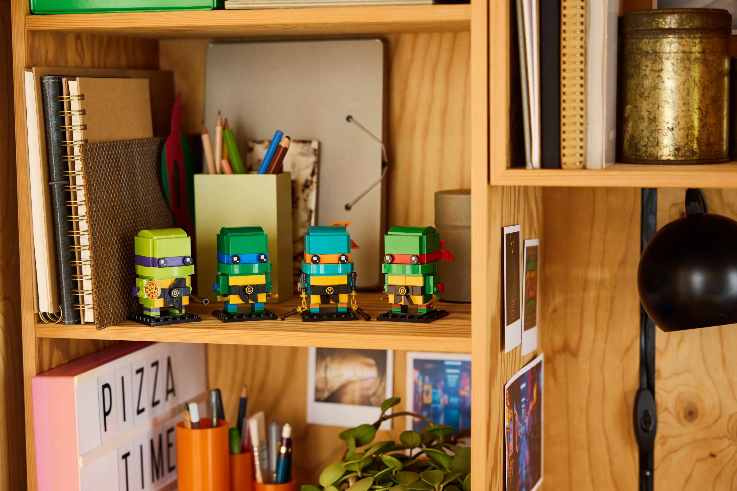 Imagine cu figurinele BrickHeadz TMNT, așezate pe o poliță printre alte obiecte decorative.