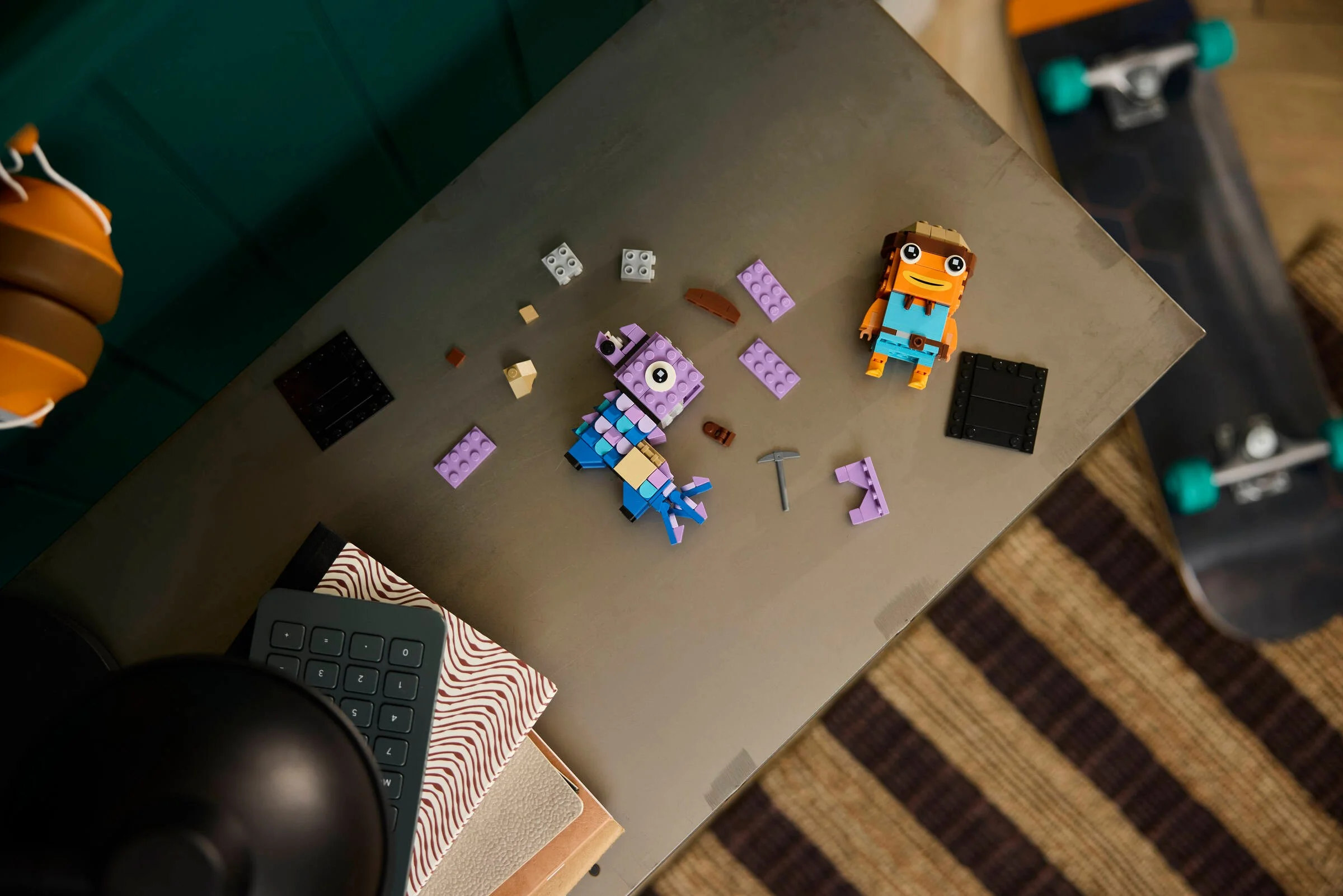 Imagine de sus cu Llama și Fishstick BrickHeadz parțial construite, pe o masă.