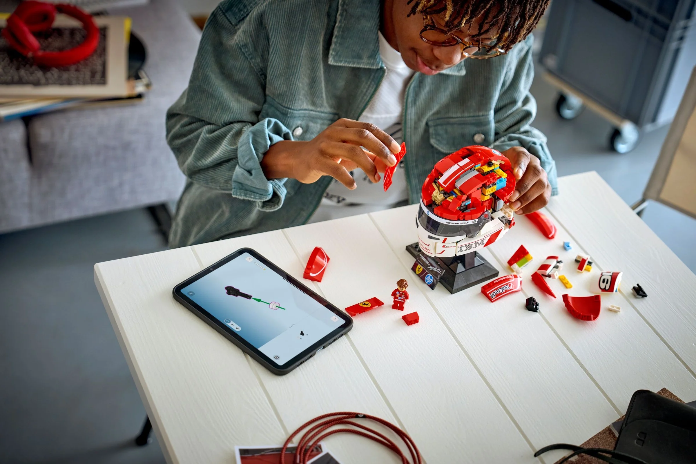 Construirea căștii Ferrari. Instrucțiuni pe tabletă, cască parțial construită, minifigurină.