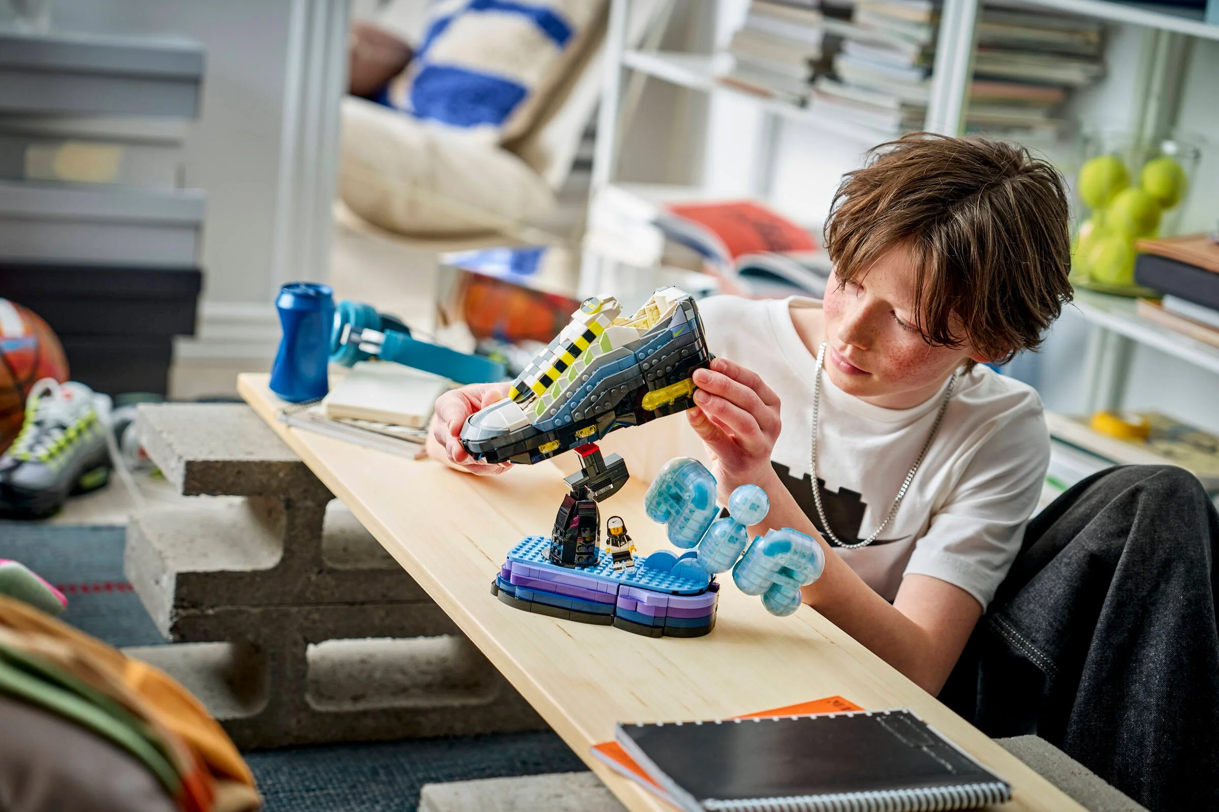 Băiat construind modelul LEGO Nike Air Max 95, concentrat și atent la detalii.
