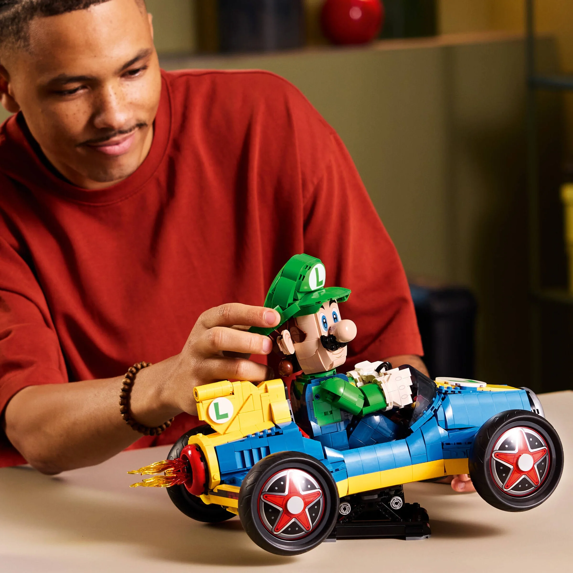 Un tânăr asamblează LEGO Mario Kart – Luigi și Mach 8, entuziasmat.