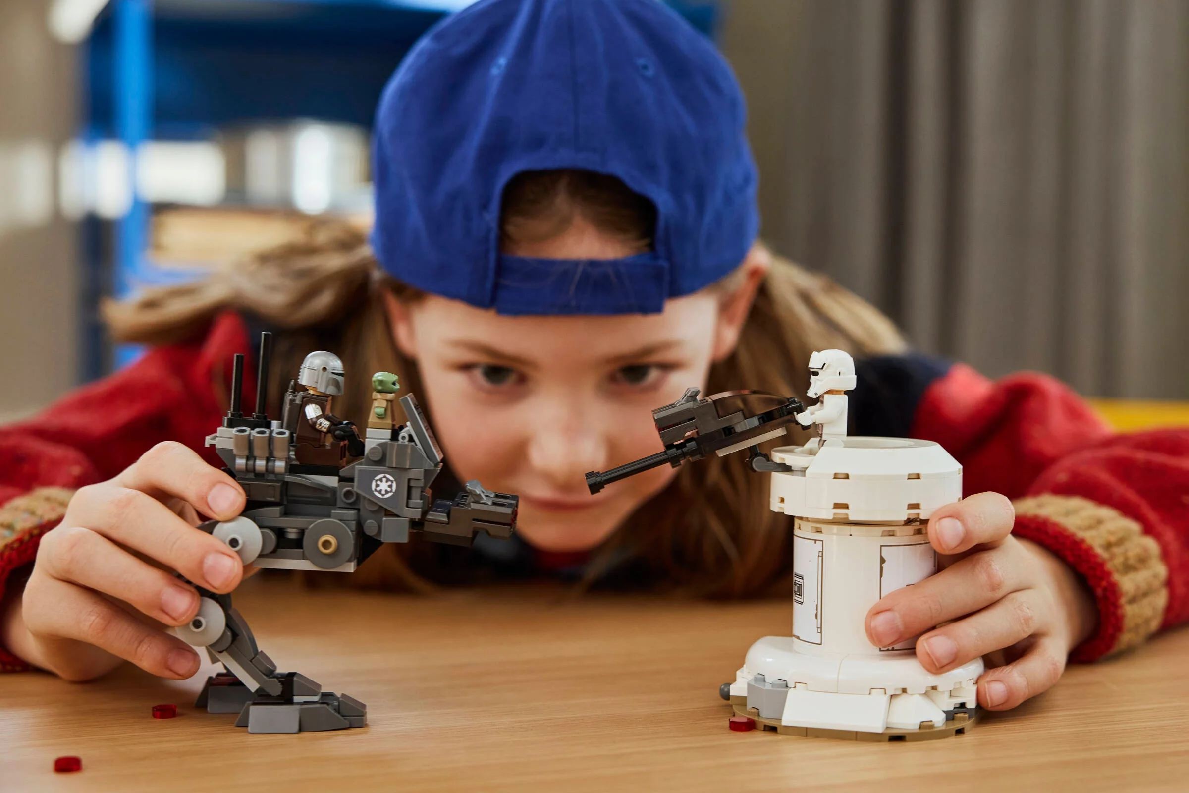 O fetiță se joacă cu setul LEGO Star Wars AT-RT Attack, simulând o bătălie imaginară.