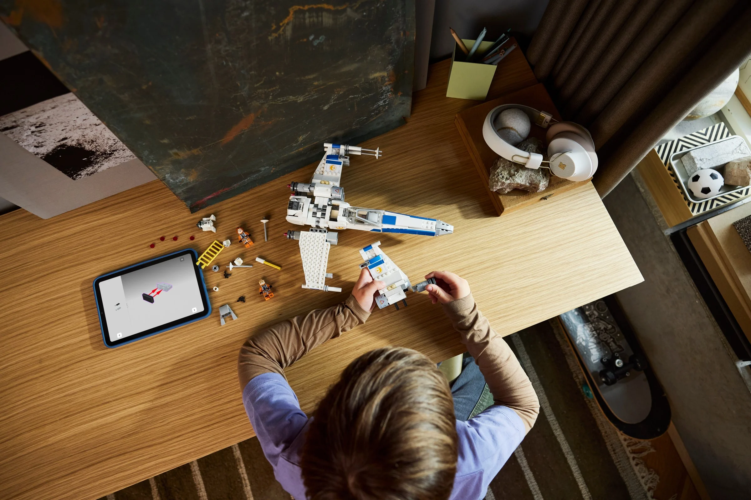 Copil construind X-wing Starfighter, folosind instrucțiuni digitale pe tabletă.