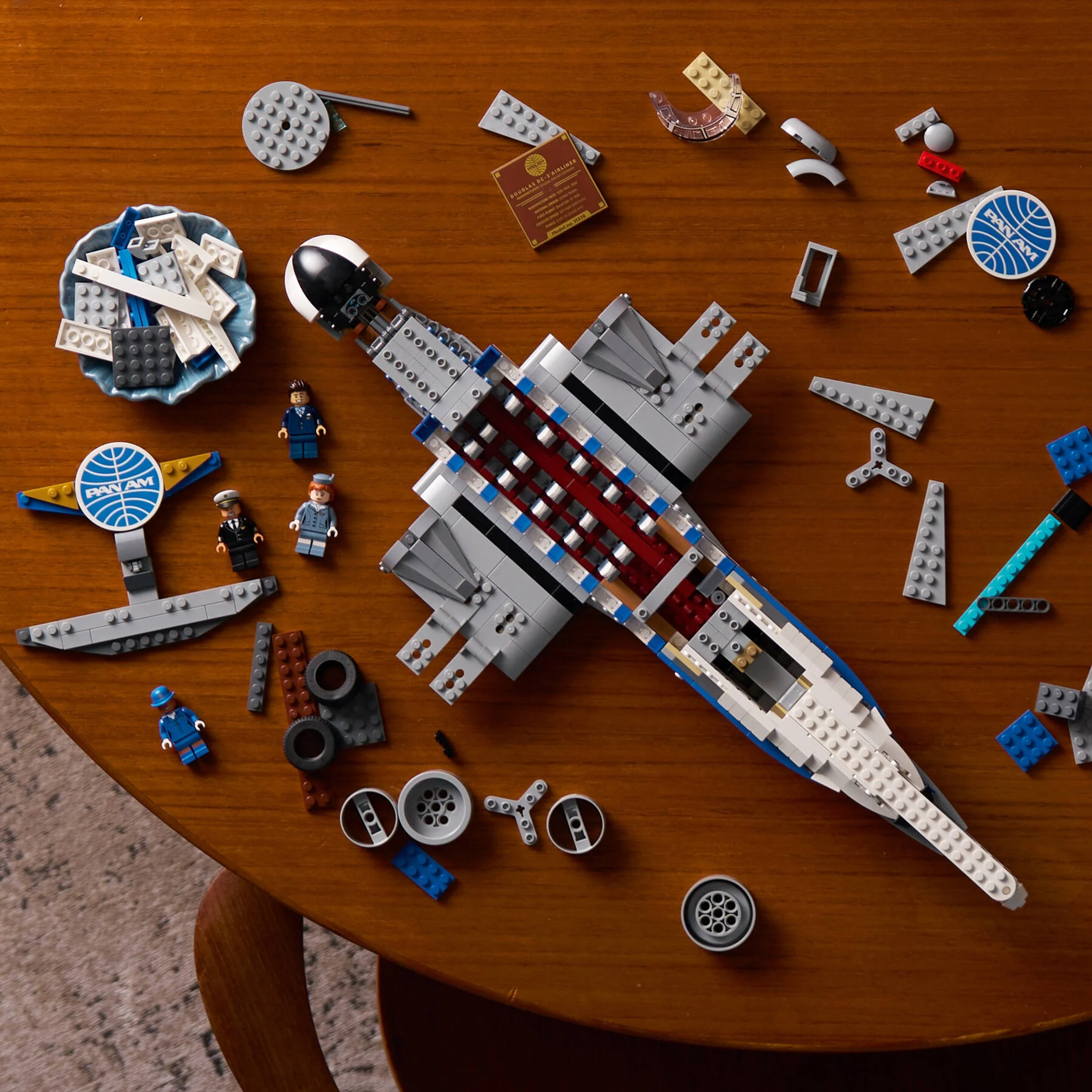 Avionul DC-3 PAN AM Lego în construcție. Piese împrăștiate, minifigurine. Aspect detaliat.