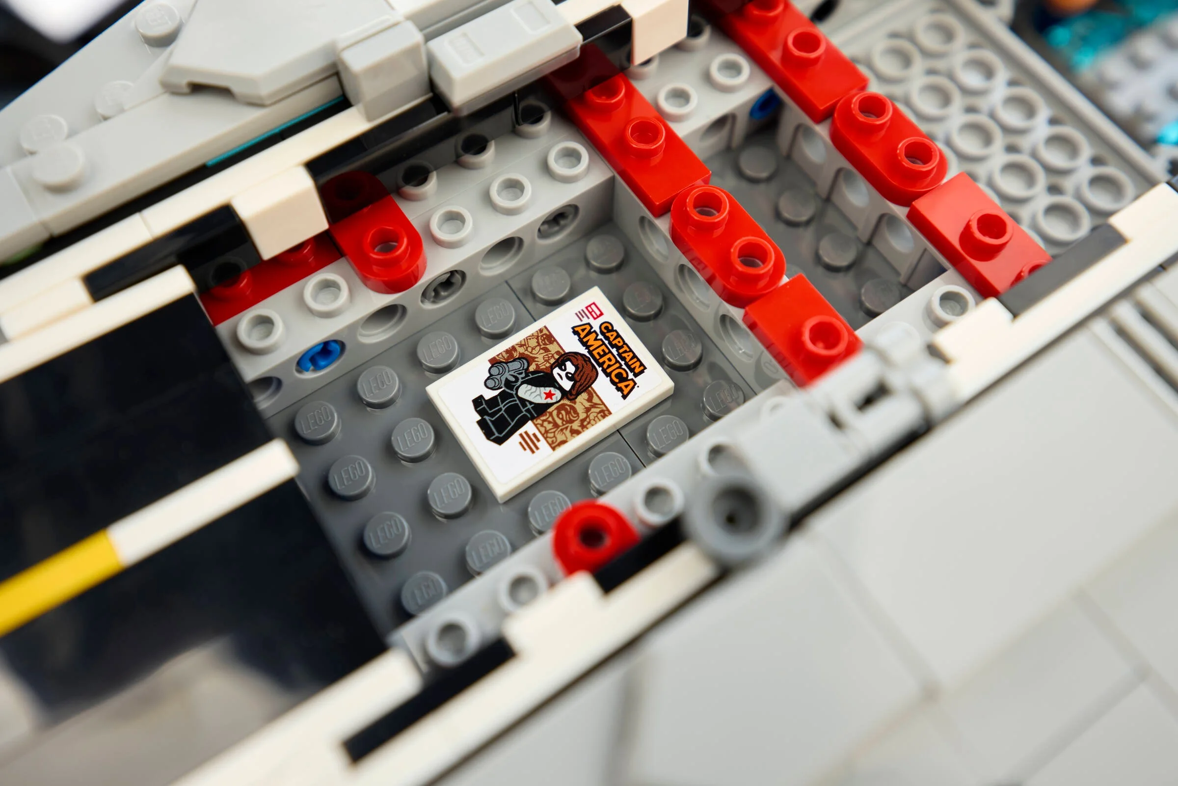 Imagine detaliată cu interiorul Helicarrierului, cu piese Lego gri și o carte Captain America.