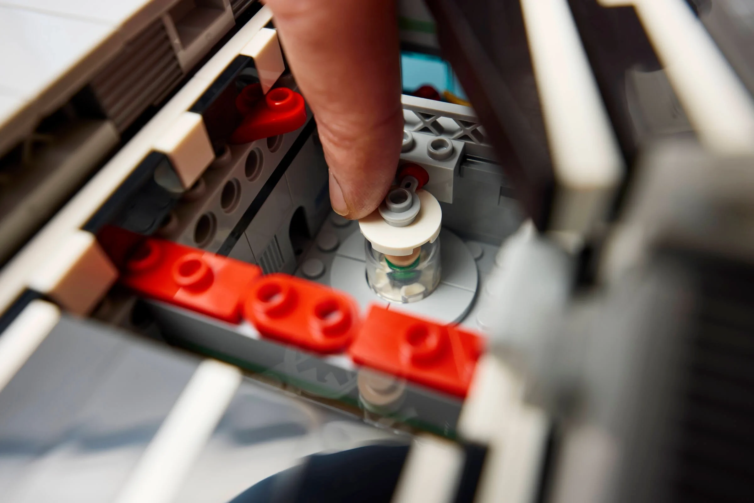 O vedere detaliată a interiorului Helicarrier-ului LEGO, cu degetul care împinge un mecanism rotativ.