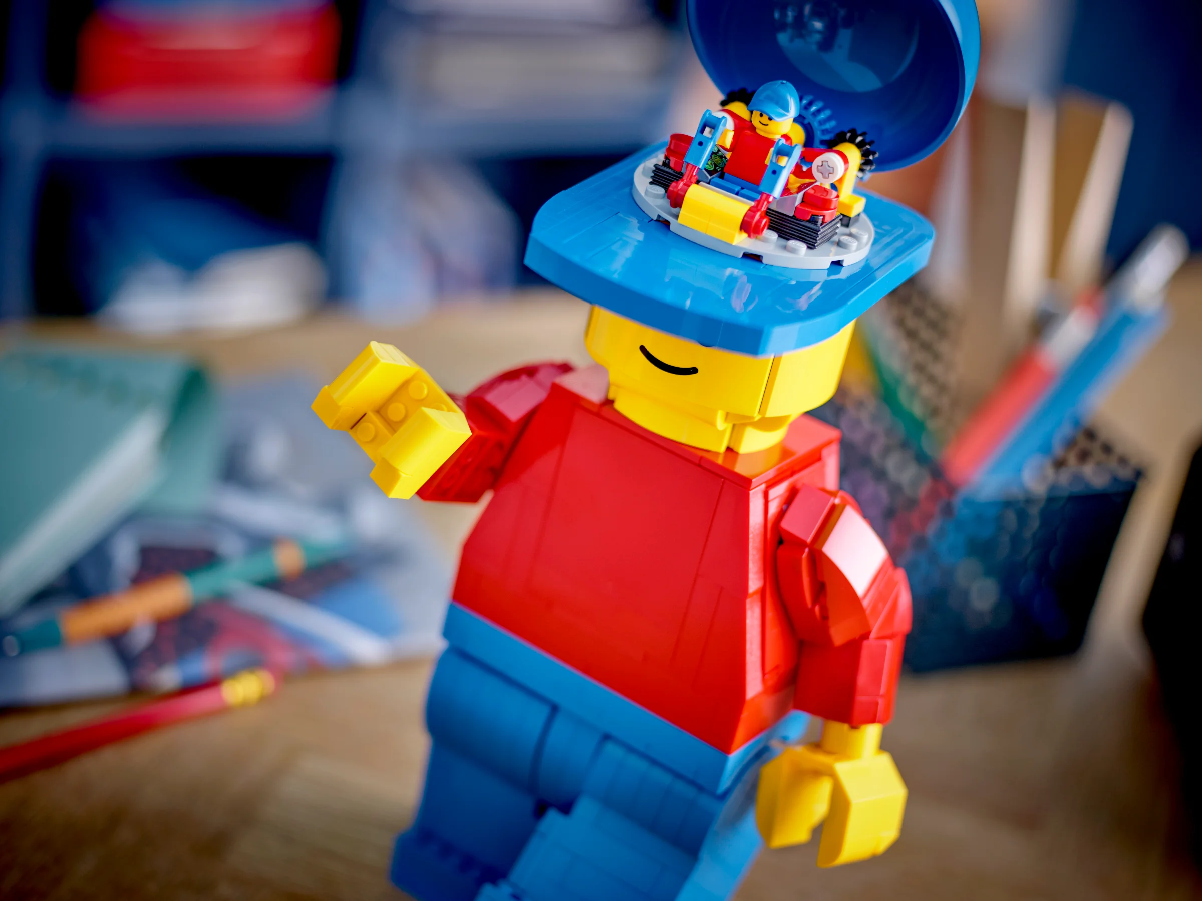 Minifigurină LEGO mărită, cu accesoriu pe cap care se deschide și dezvăluie mini-minifigurine.