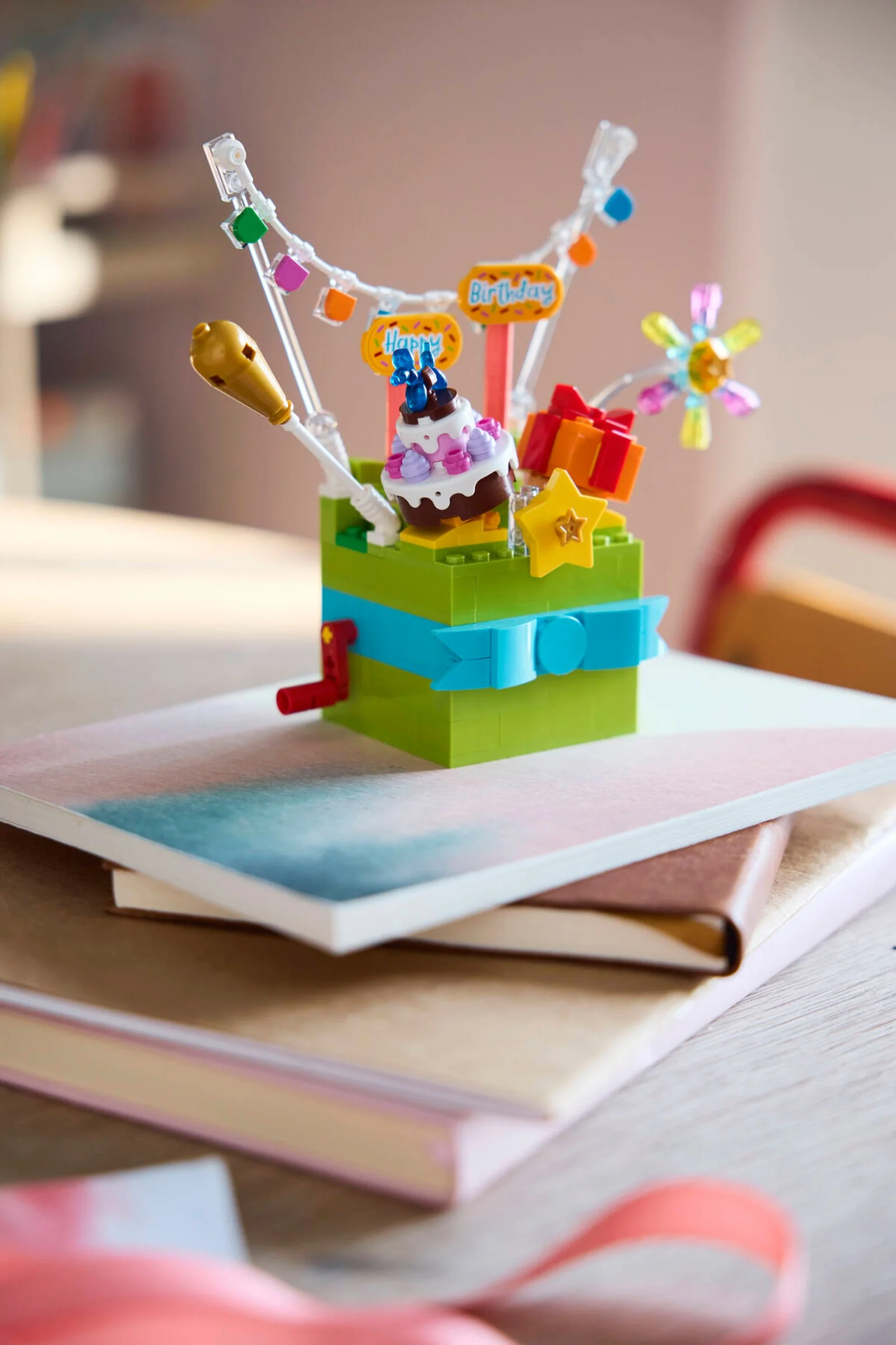 Cutie LEGO de cadou aniversară cu tort, stea, cadou și stegulețe vesele.