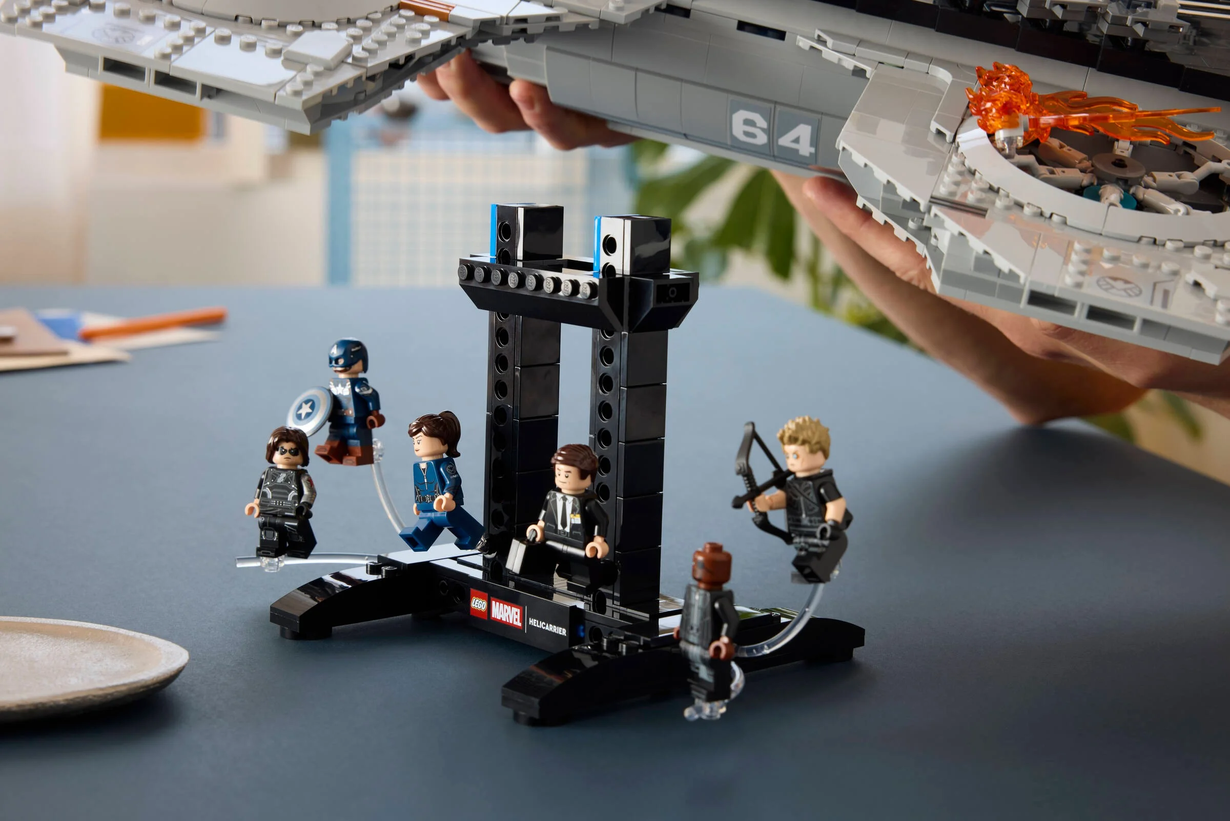 Imagine prezintă minifigurinele din setul LEGO Helicarrier pe un suport. Detalii despre Helicarrier sunt vizibile.