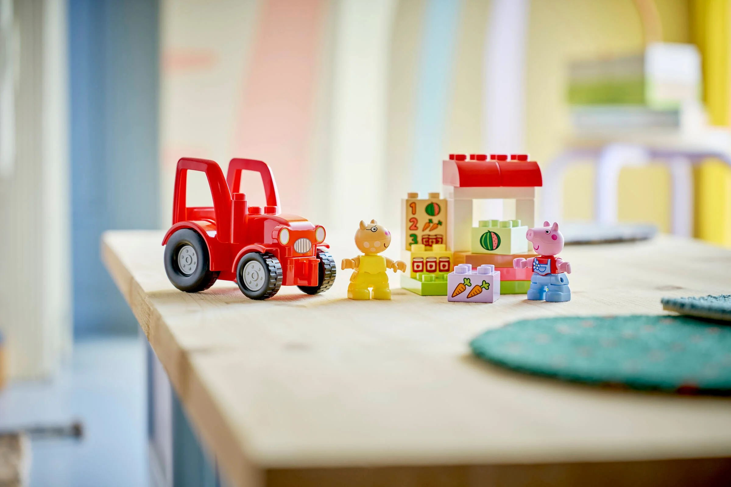 Imagine cu tractorul, piața și minifigurinele Duplo. Set atractiv, viu colorat, pentru copii mici.