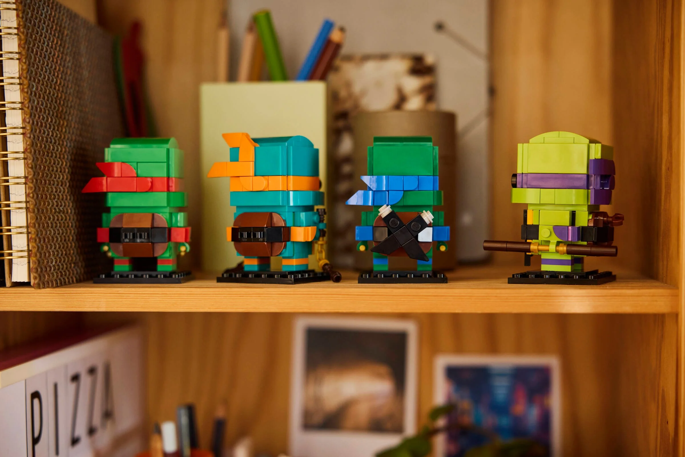 Imagine cu cele patru figurine BrickHeadz Testoasele Ninja stând pe o poliță de lemn.