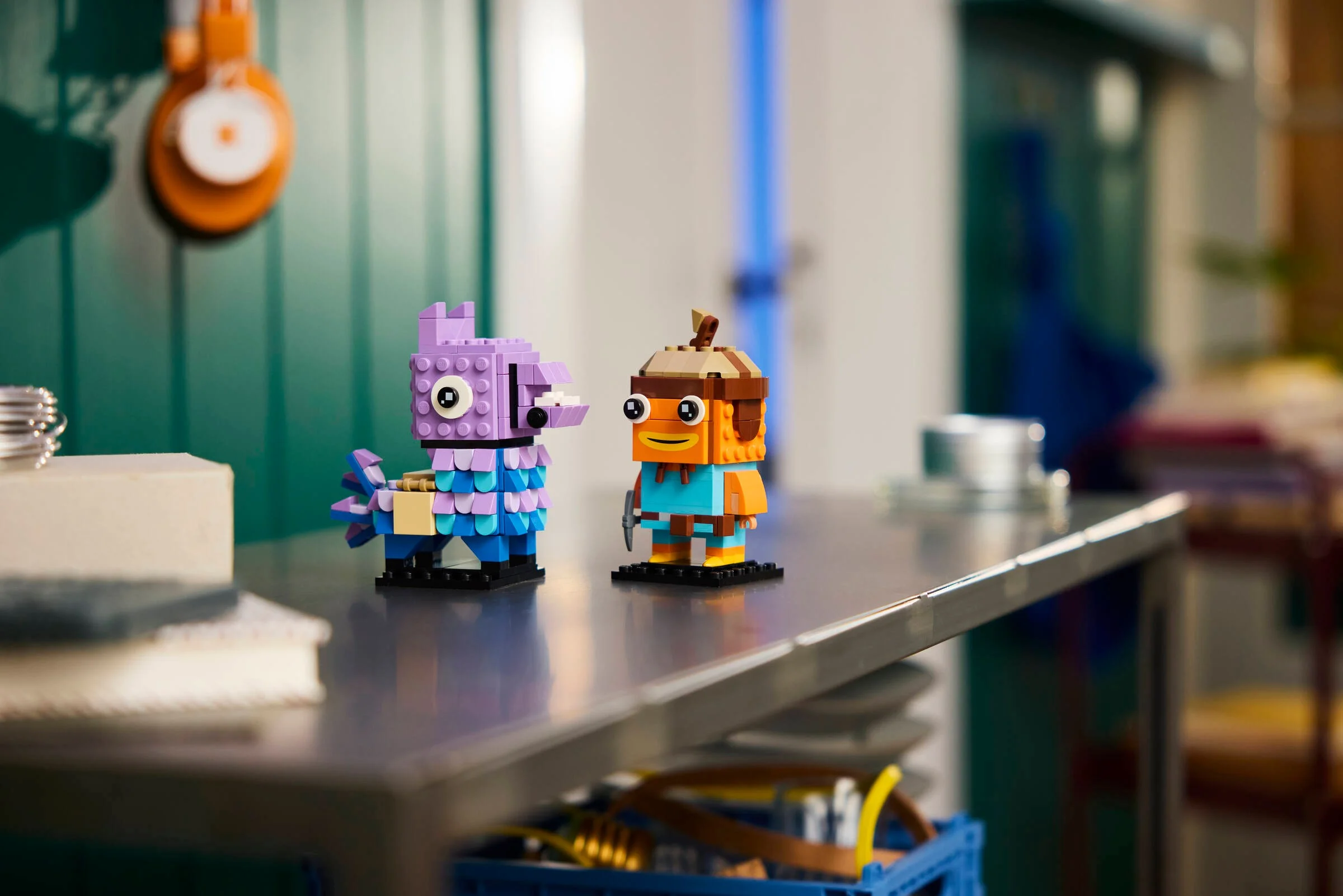 Imagine cu setul LEGO BrickHeadz 40881: Supply Llama și Fishstick, pe o masă. Distractiv și colorat.