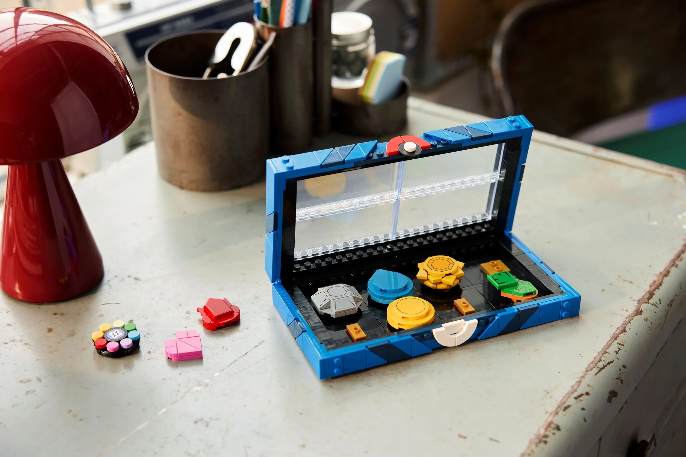 Colecția de insigne Kanto LEGO, cu cutia deschisă și câteva insigne alături.
