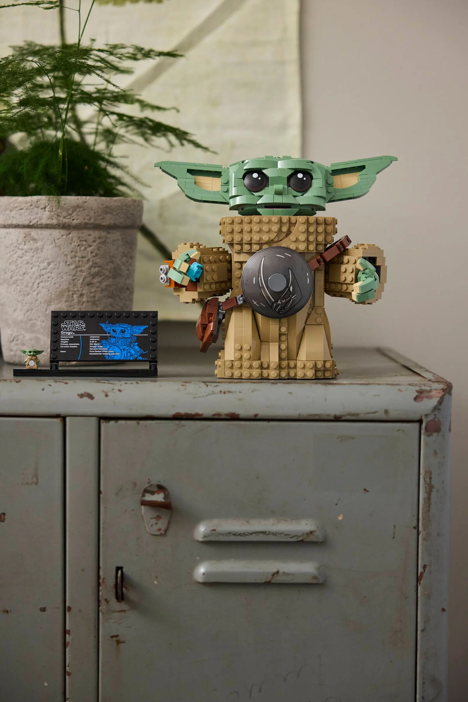 Grogu LEGO Star Wars, o figurină adorabilă și un afișaj informativ pe un dulap vechi.