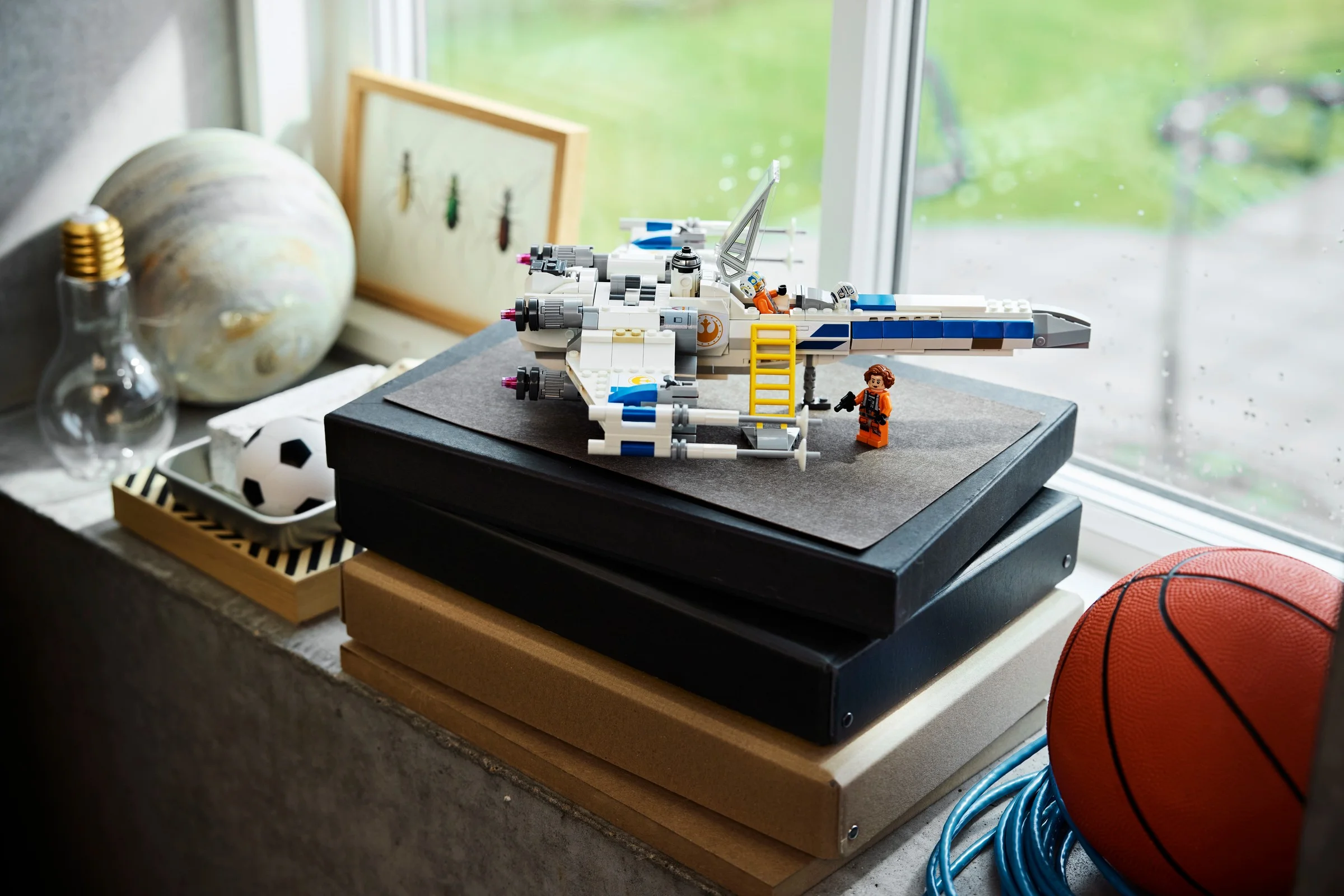 O imagine cu modelul LEGO X-wing, însoțit de două minifigurine Star Wars.