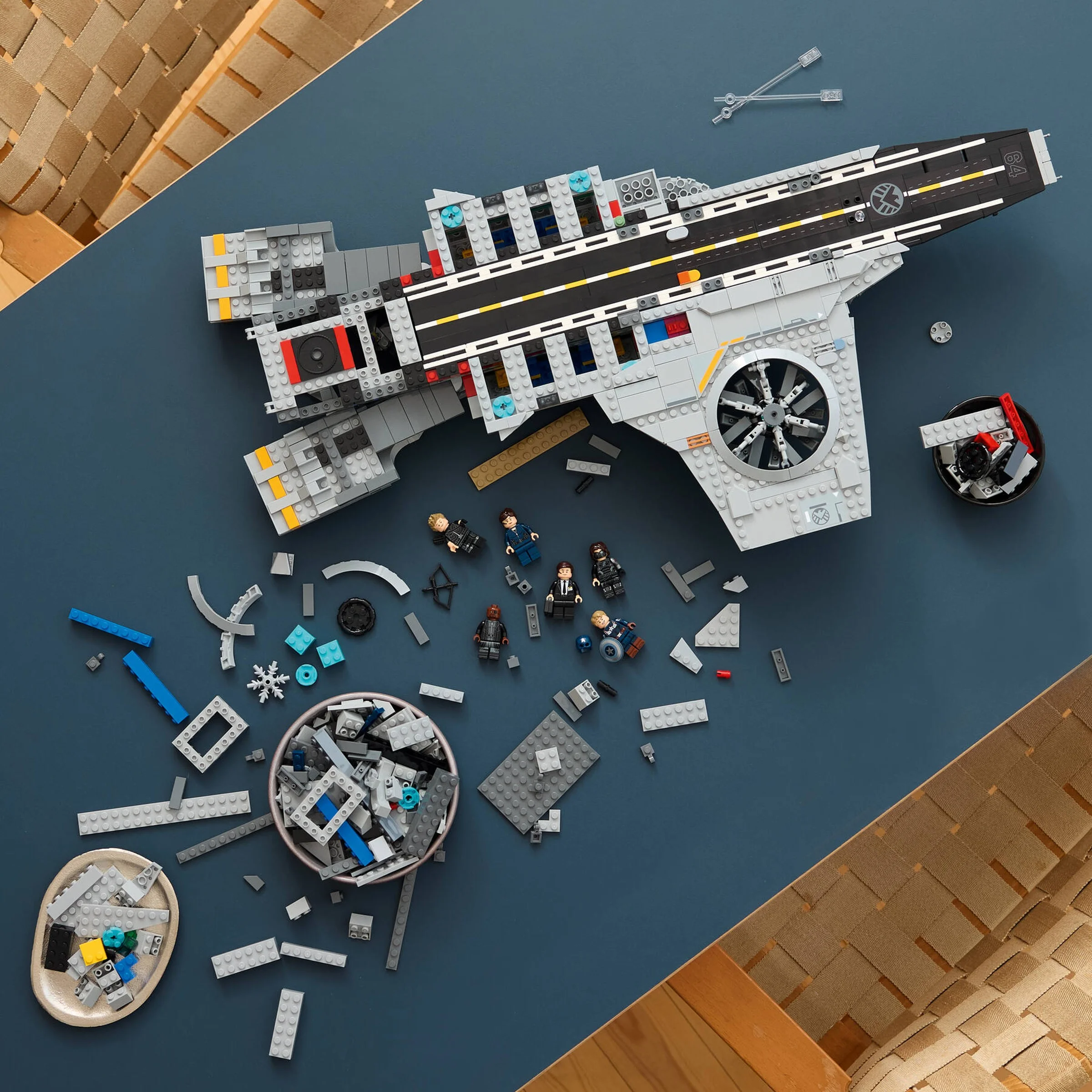 Helicarrier S.H.I.E.L.D. LEGO parțial asamblat, cu minifigurine și piese împrăștiate.