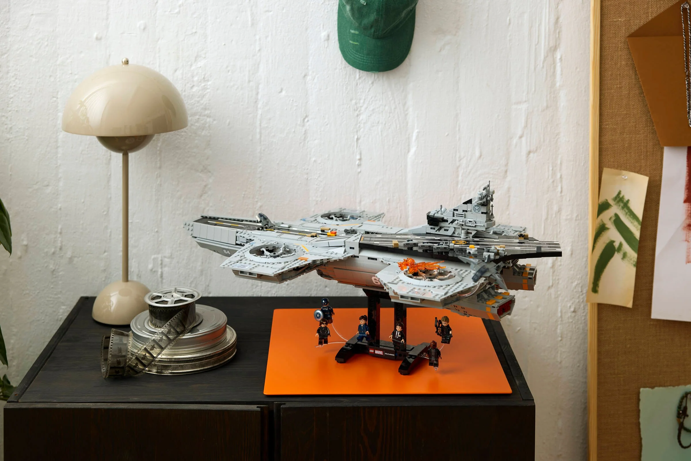 Helicarrier S.H.I.E.L.D. LEGO pe un suport, încadrat într-un decor cotidian.