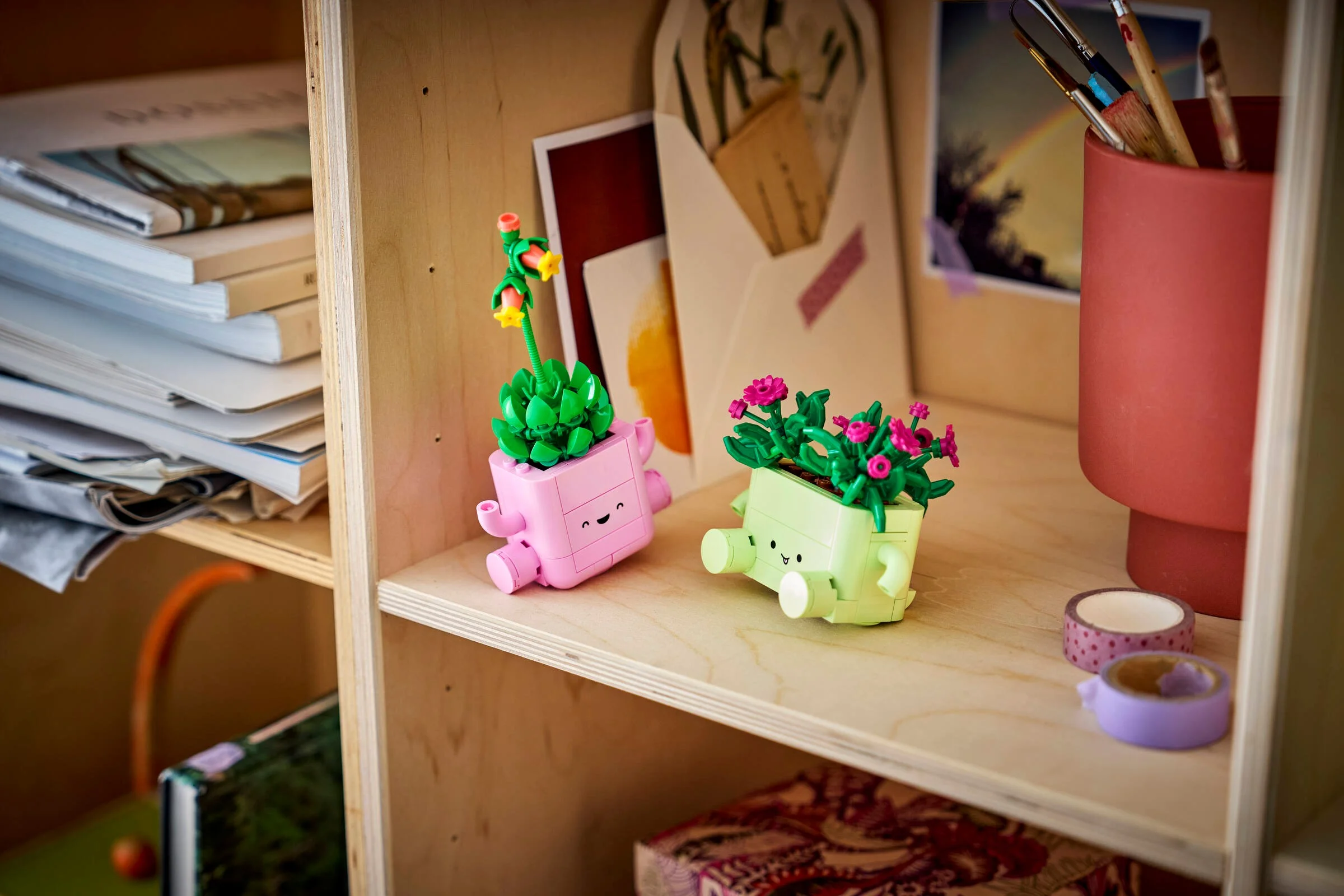 Două plante LEGO care se balansează, un cactus roz și o plantă verde cu flori roz.