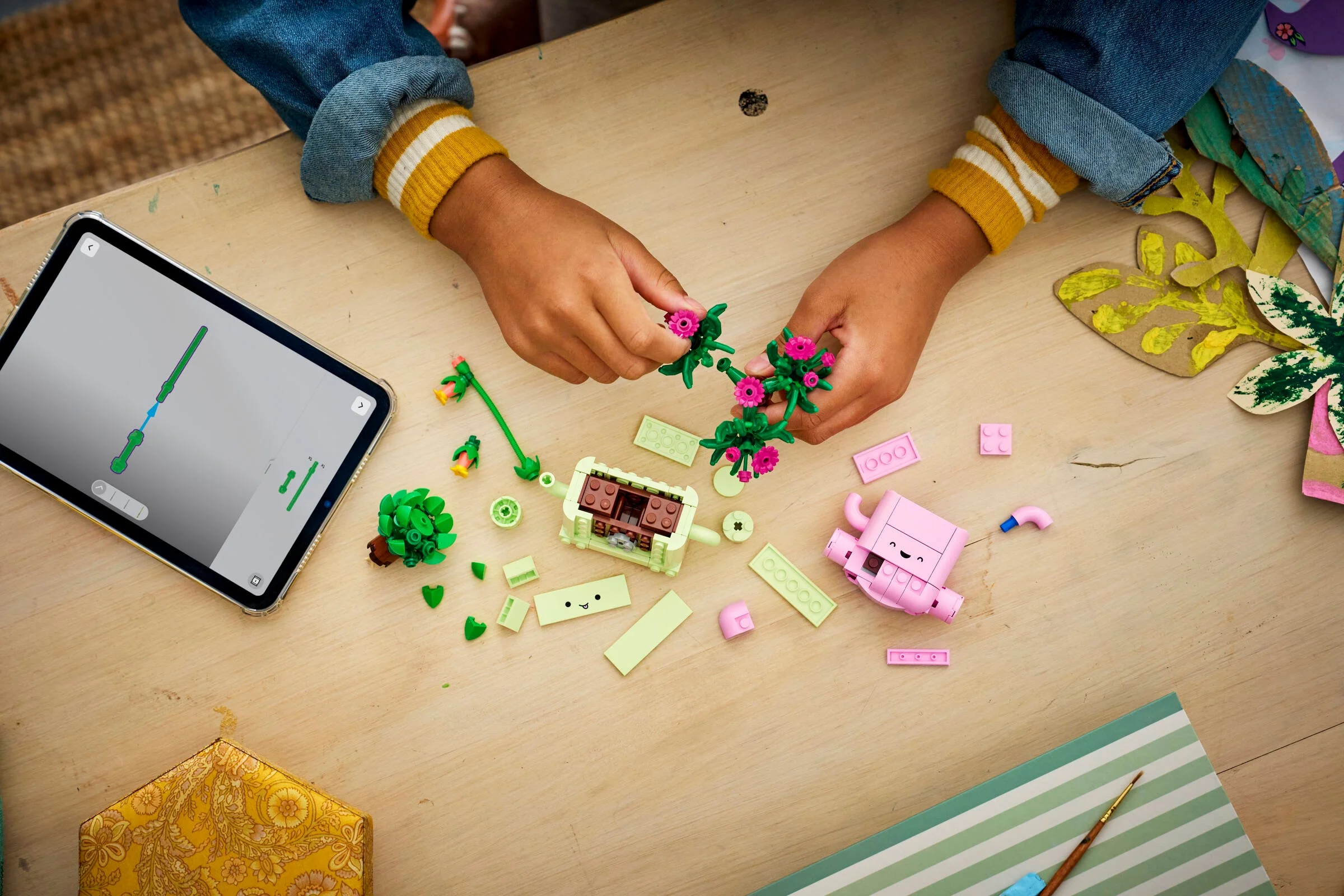 Imagine de sus cu setul LEGO Rocking Plants 11506 în construcție, cu mâini de copil.