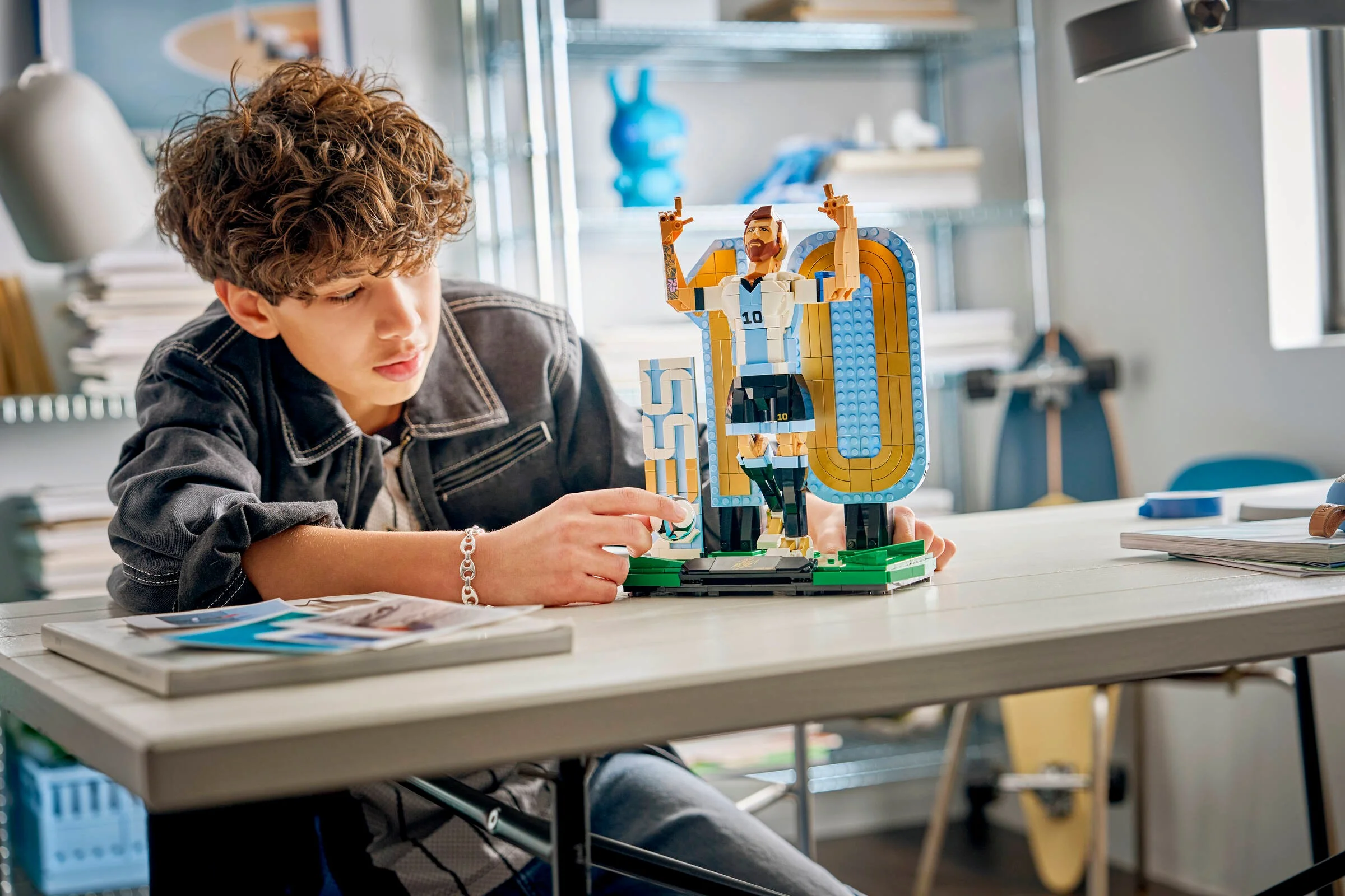 Un tânăr construiește cu atenție setul LEGO Lionel Messi, bucurându-se de activitate.