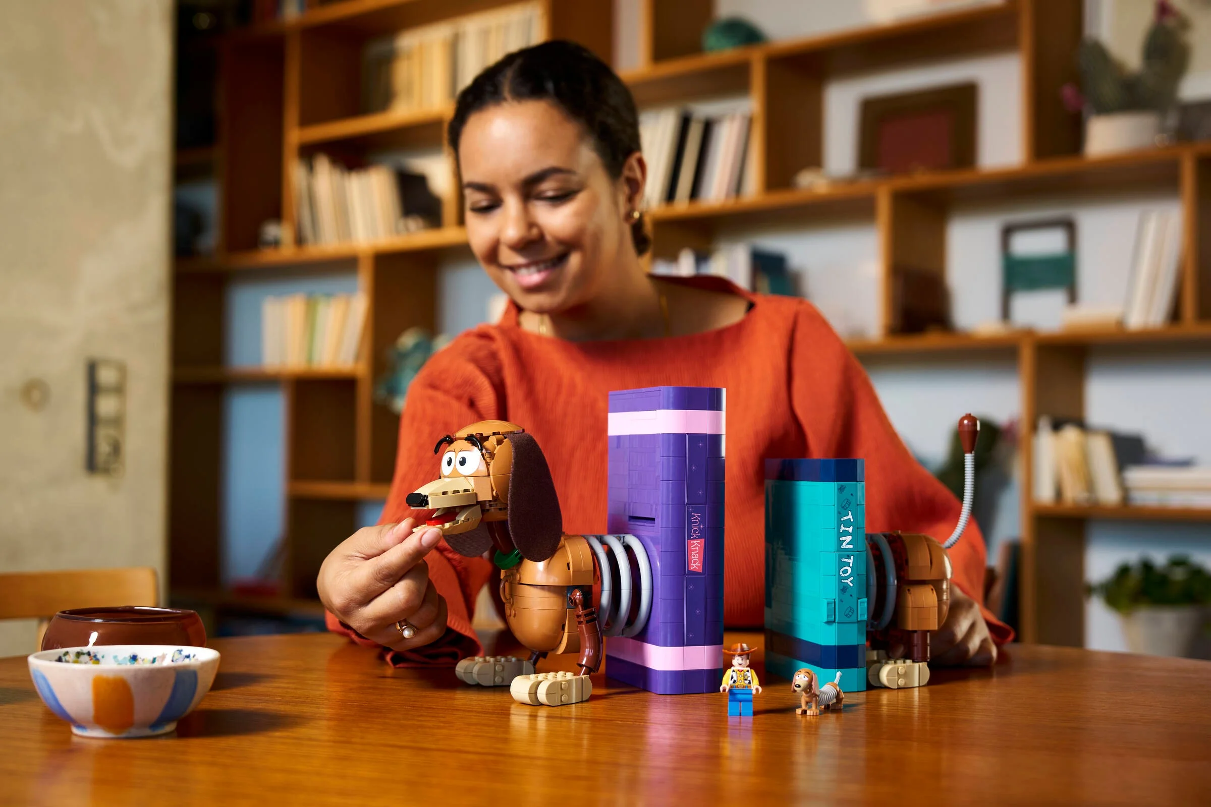 O persoană asamblează Slinky Dog din setul LEGO 43301, cu minifigurinele incluse.