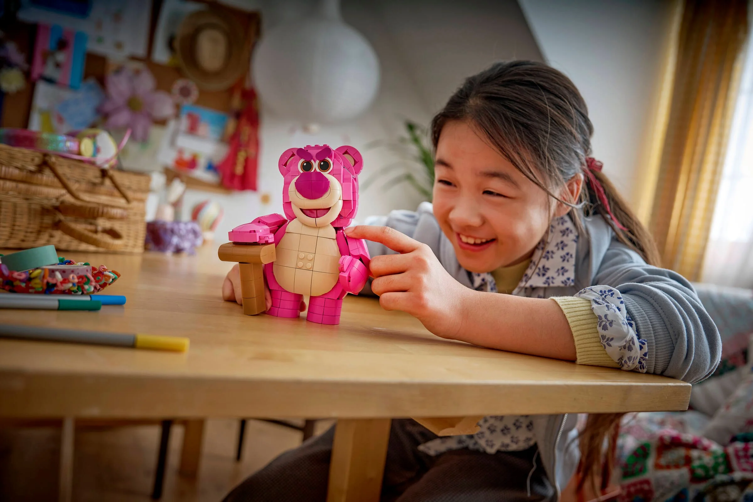 Fetiță zâmbitoare se joacă cu Lotso LEGO la o masă. Un cadru cald și prietenos.