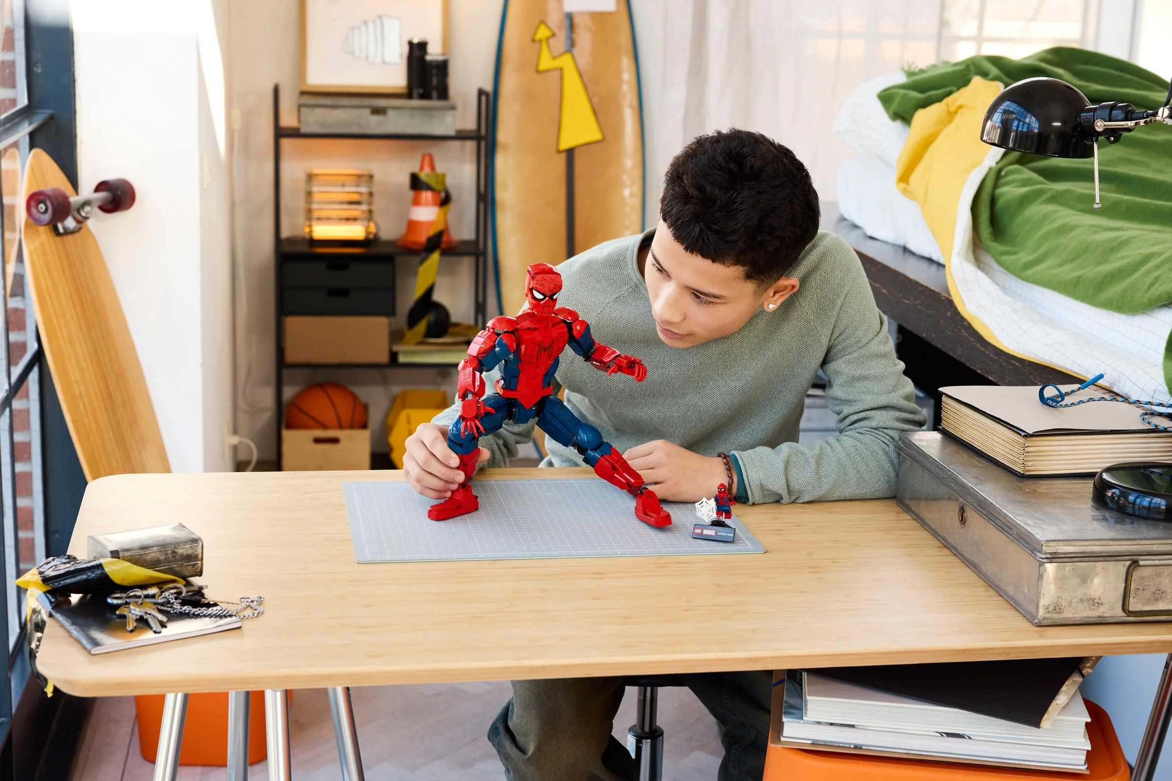Imagine cu un tânăr interacționând cu figurina Spider-Man LEGO, într-un cadru casual.