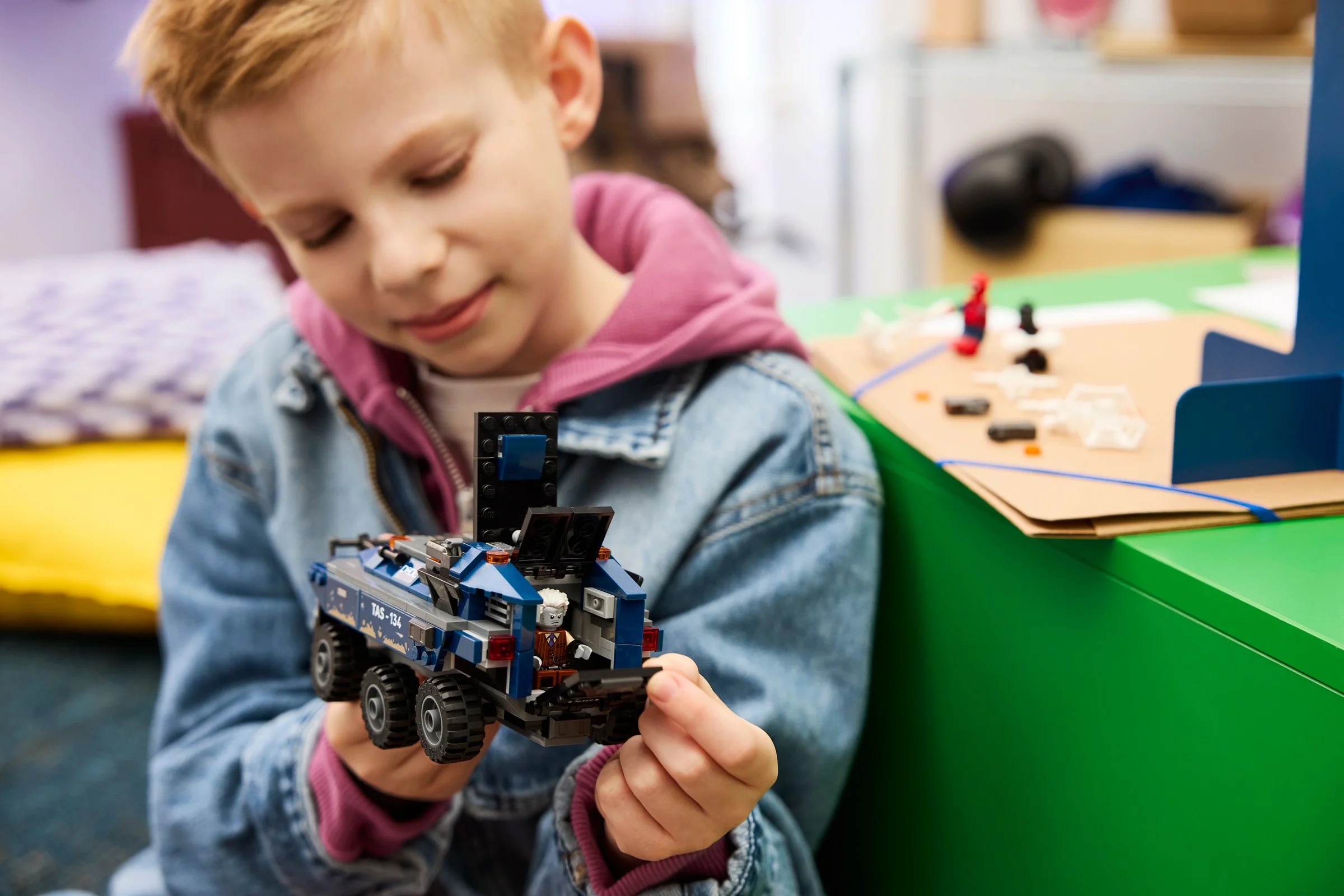Un copil se uită la transportorul închisoare LEGO Spider-Man. Interacțiune și joacă.