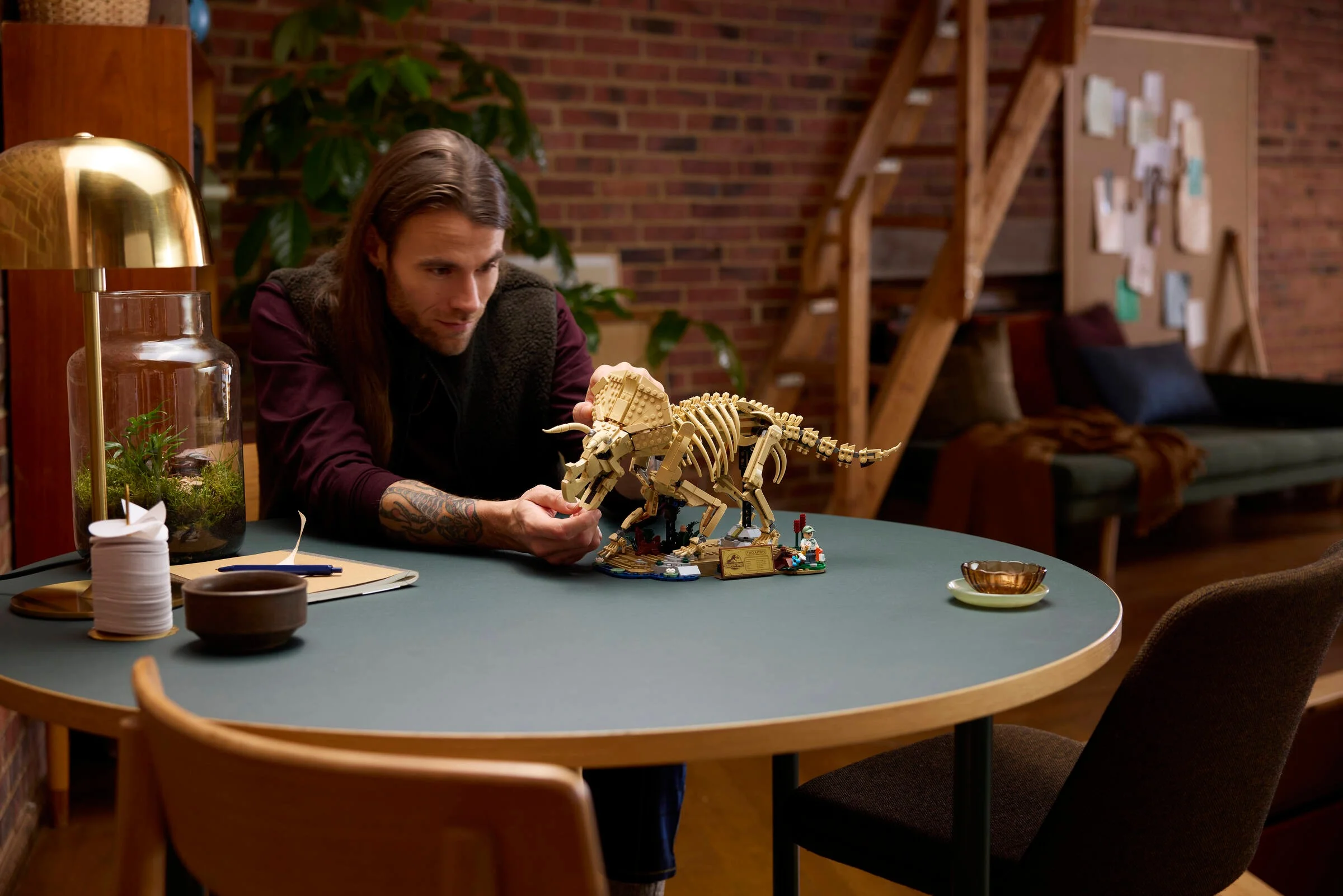 O persoană admiră scheletul LEGO Triceratops, într-o scenă ambiantă de interior.