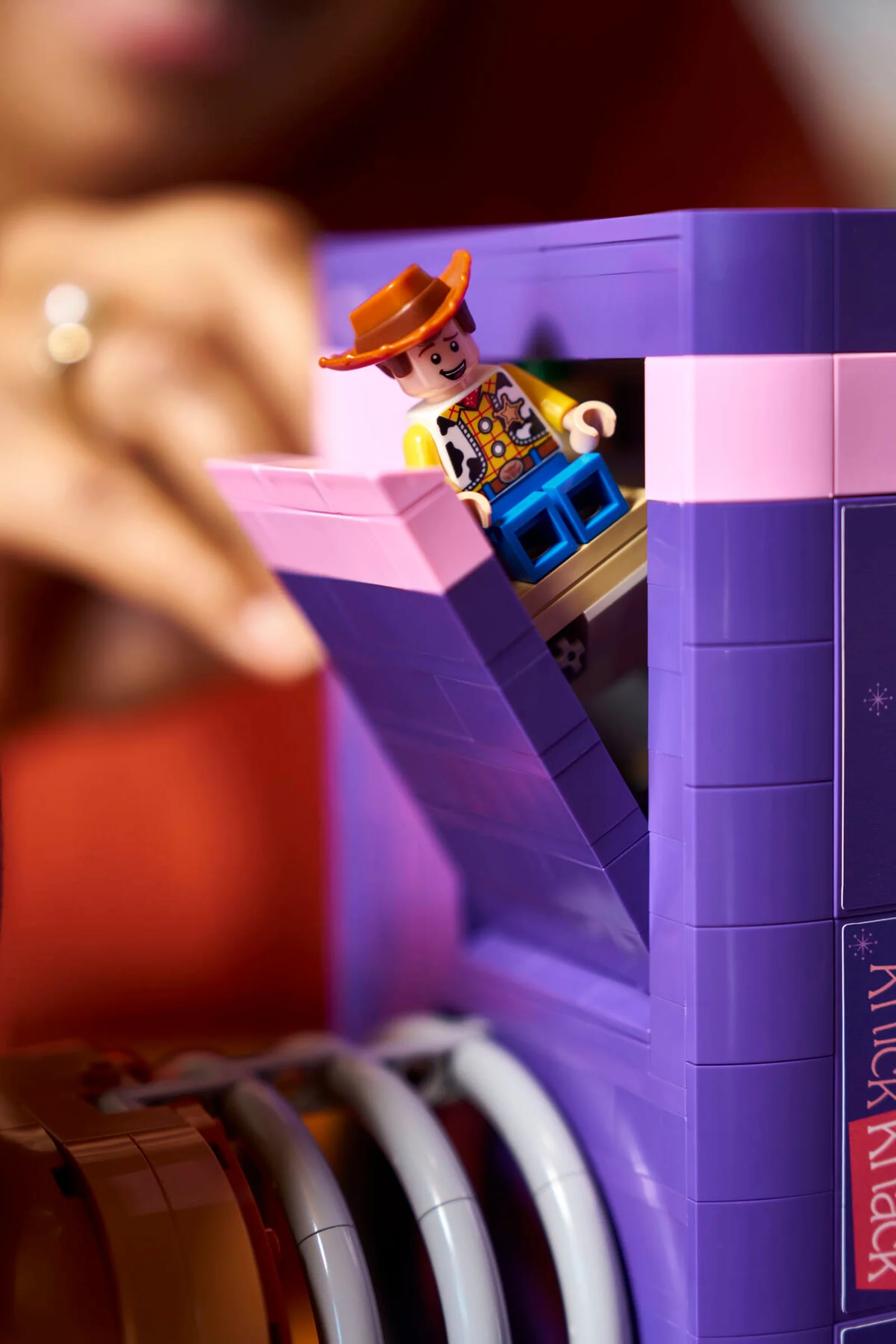 Prim plan cu mini-figura LEGO Woody pe o secțiune a suportului de cărți Slinky Dog. Focus pe detaliile construcției.