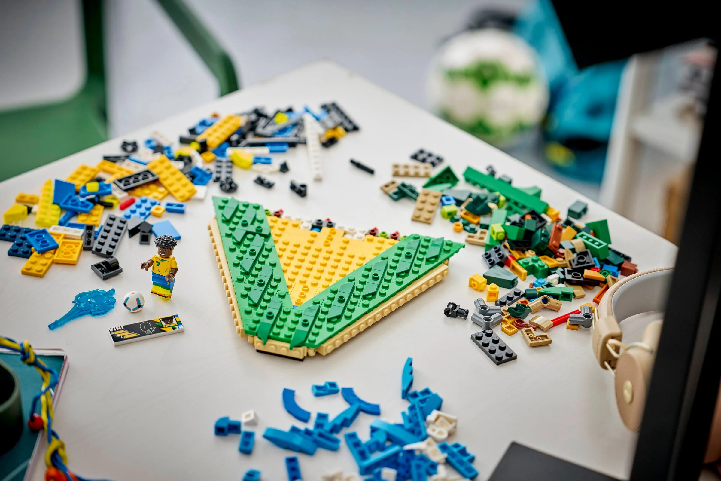 Construirea scenei Vini Jr., cu minifigurina și piese LEGO împrăștiate pe masă.