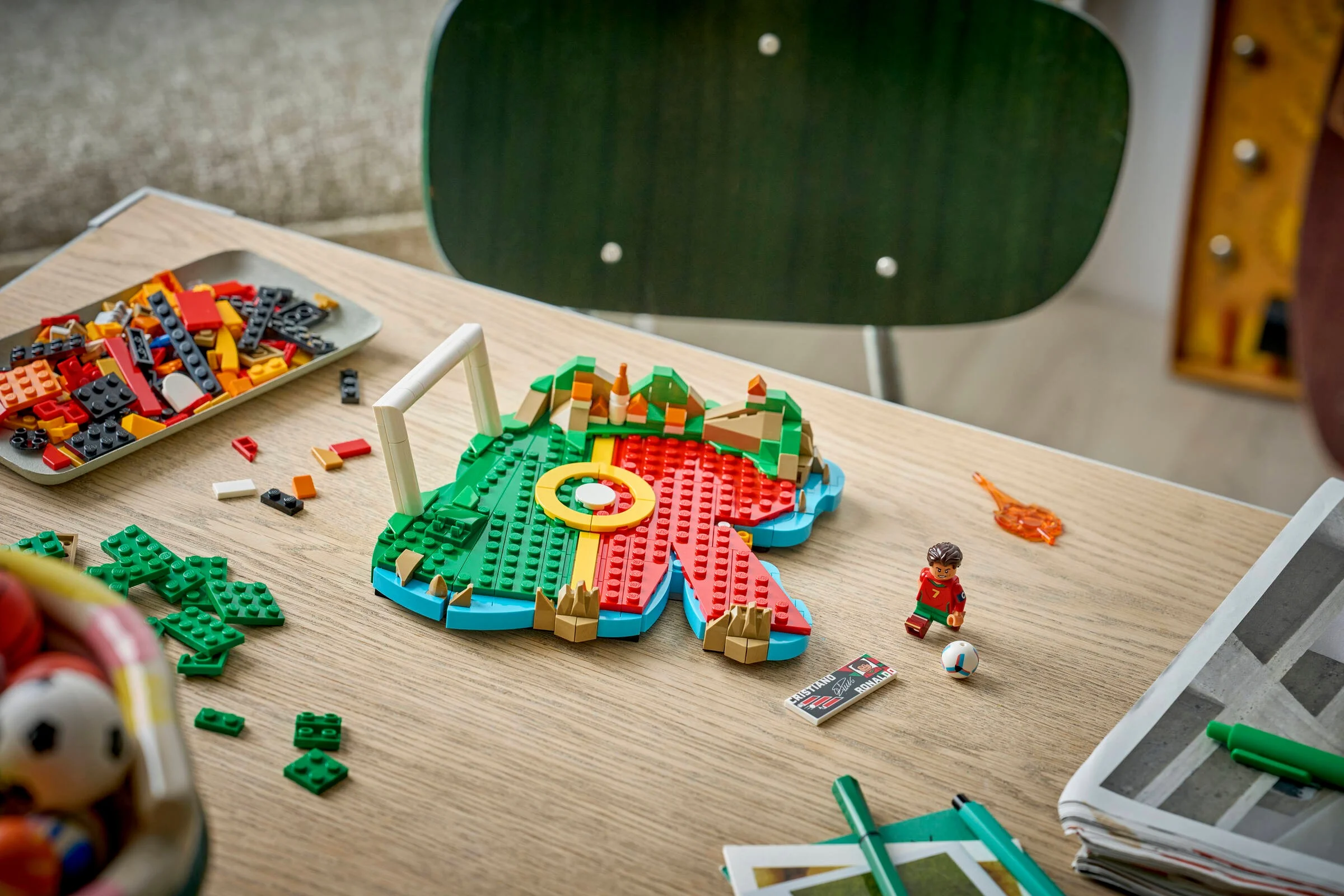 Imagine arată modelul LEGO Cristiano Ronaldo în construcție, cu minifigurina și piese împrăștiate.