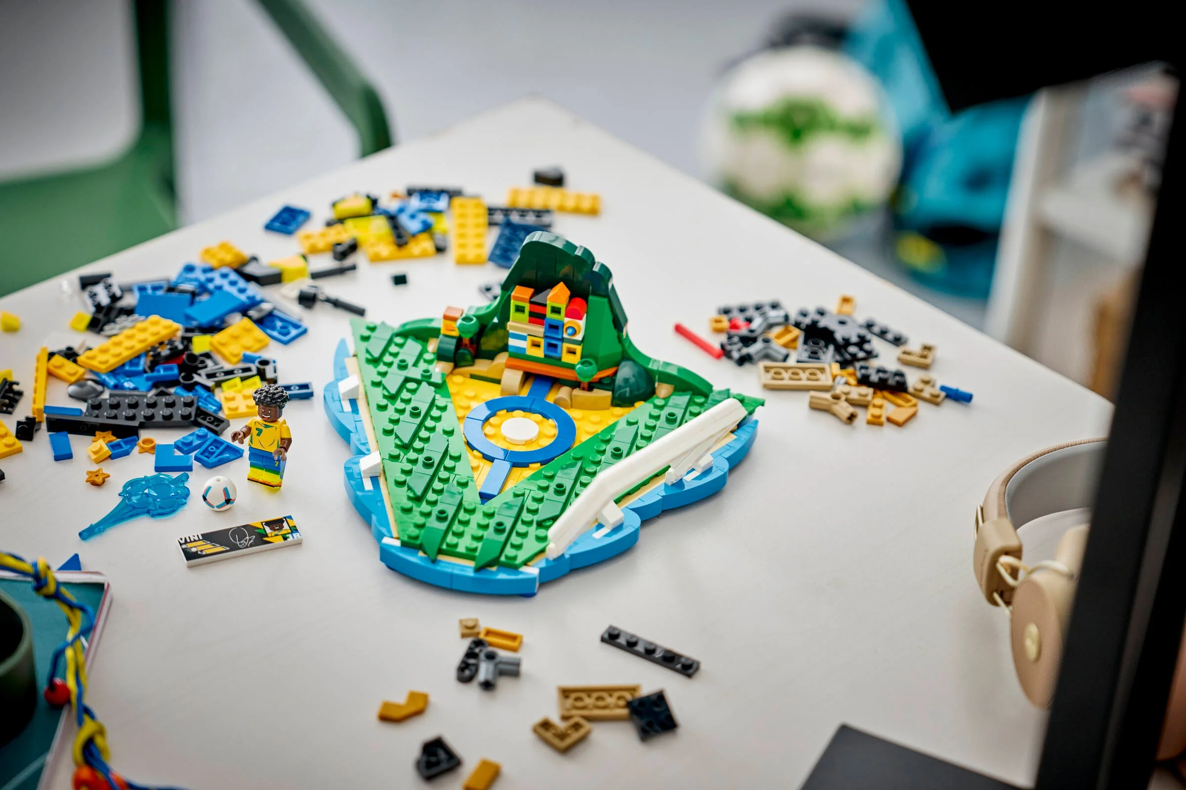 Construcția LEGO Vini Jr. parțial asamblată, cu minifigurina și piese împrăștiate pe masă.