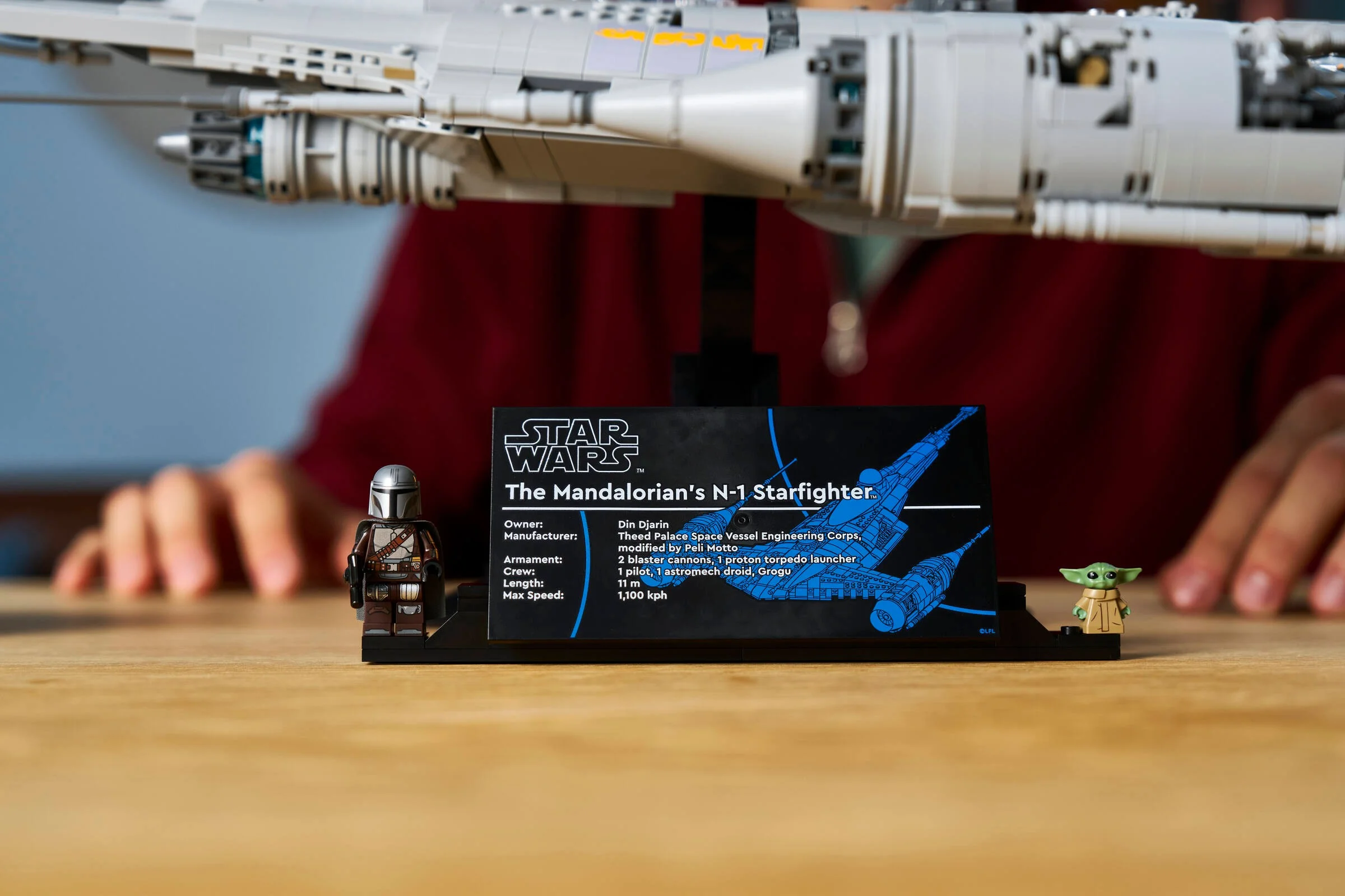 Imagine cu N-1 Starfighter, minifigurinele Mandalorian și Grogu, plus panoul cu informații.