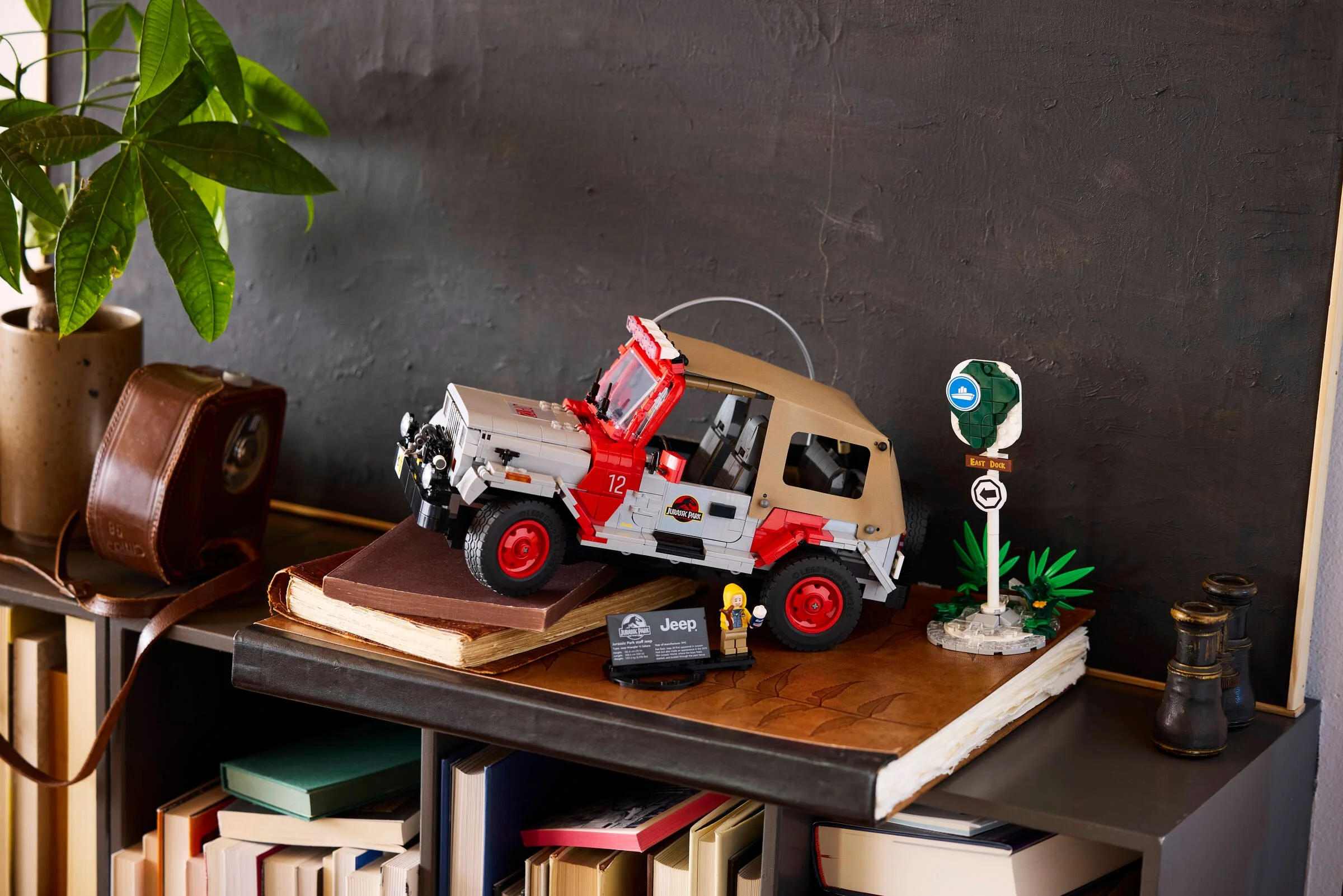 Imagine cu Jeep-ul Jurassic Park LEGO (77984) pe o etajeră, alături de minifigurină și indicatoare.