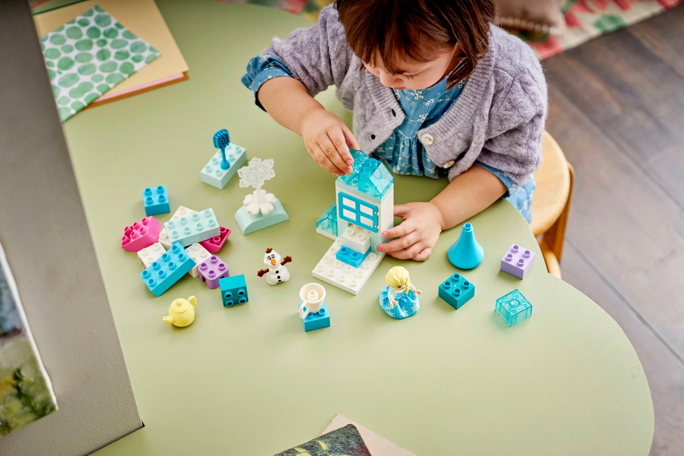 O fetiță se joacă cu setul LEGO DUPLO Frozen Creative Box, construind o căsuță de gheață.