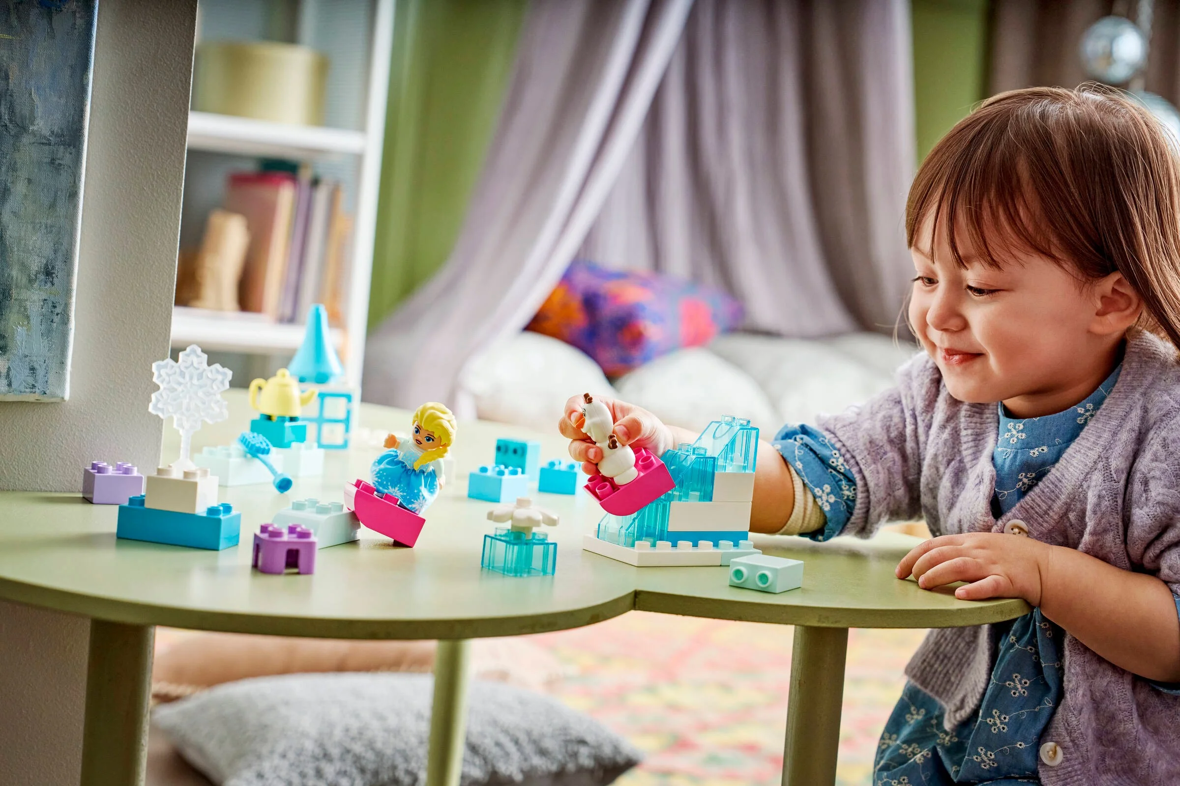 Fetiță se joacă cu setul LEGO DUPLO Frozen. Elsa și Olaf sunt prezenți.