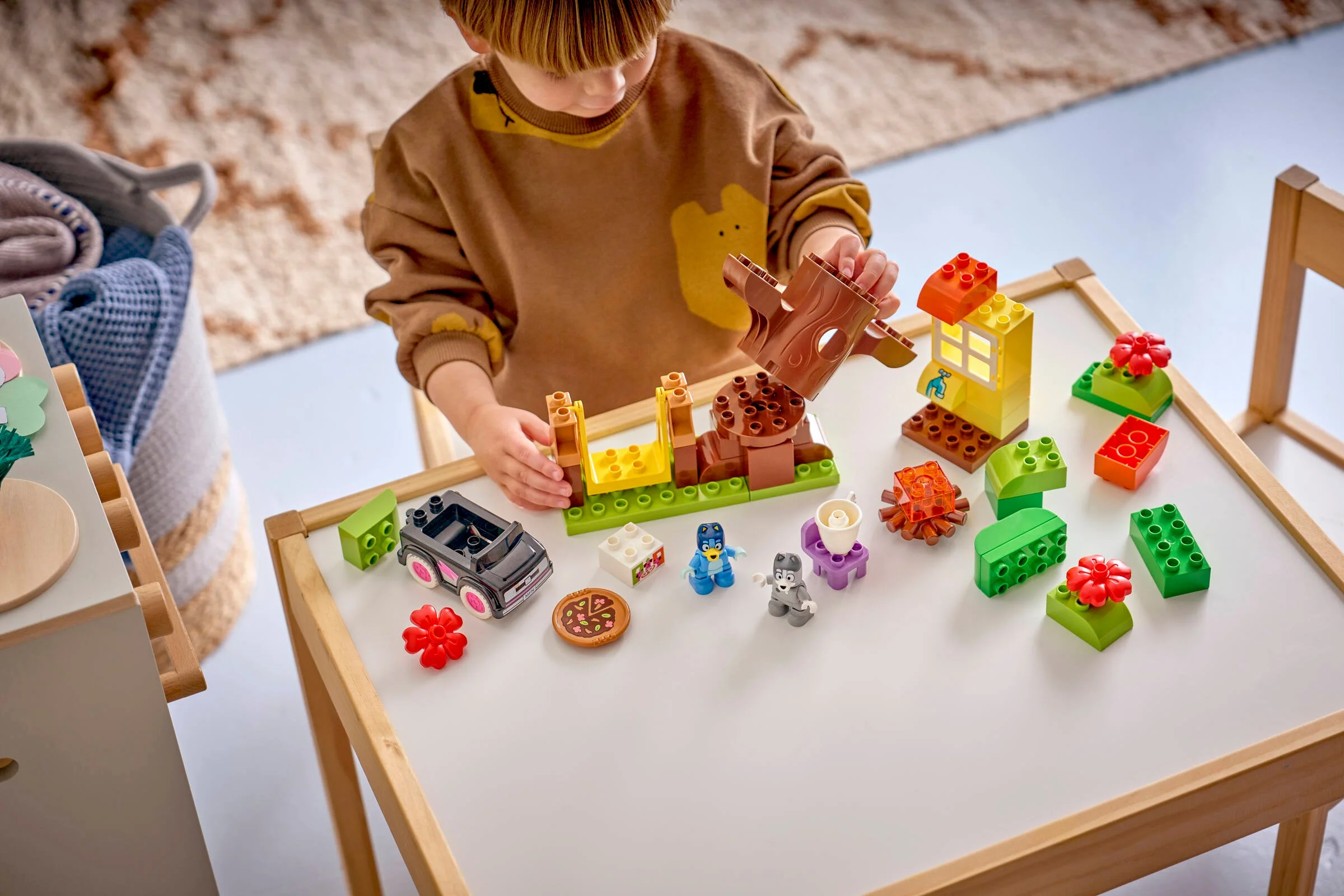 Copil se joacă cu setul LEGO DUPLO 10469. Piesele sunt colorate și distractive.