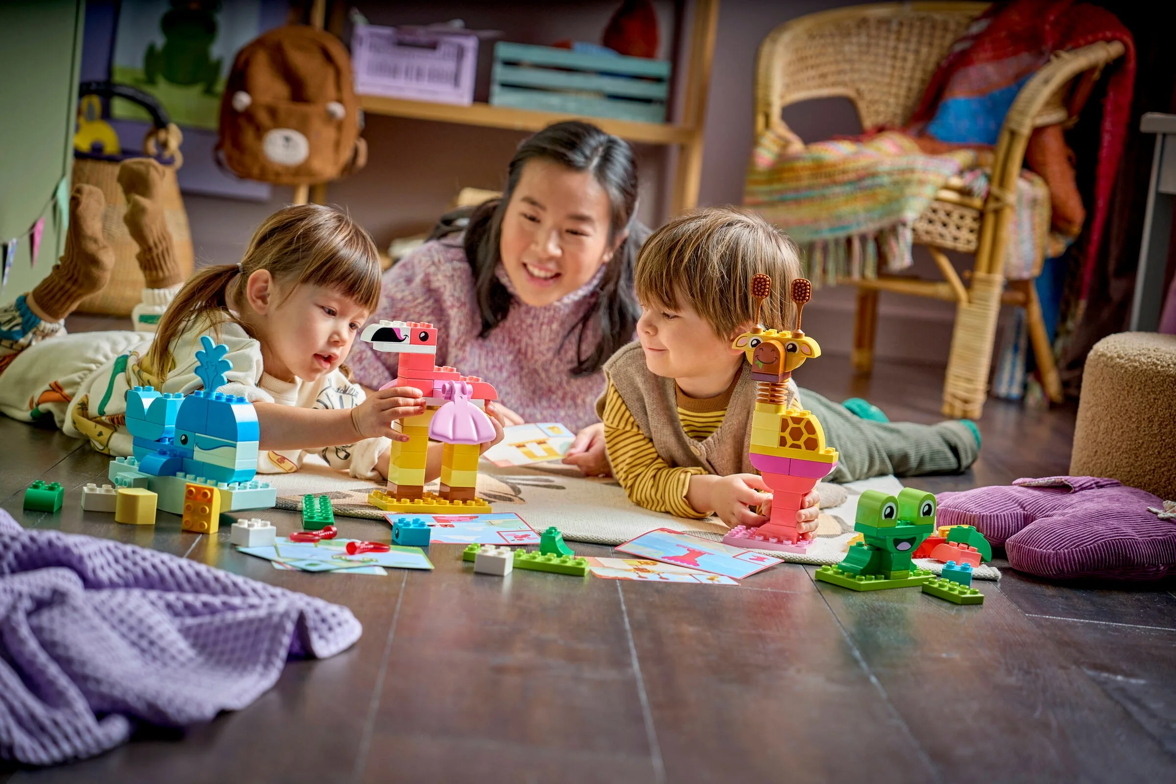 Copii și un adult construind animale LEGO DUPLO. Joc distractiv și creativ pentru copii mici.