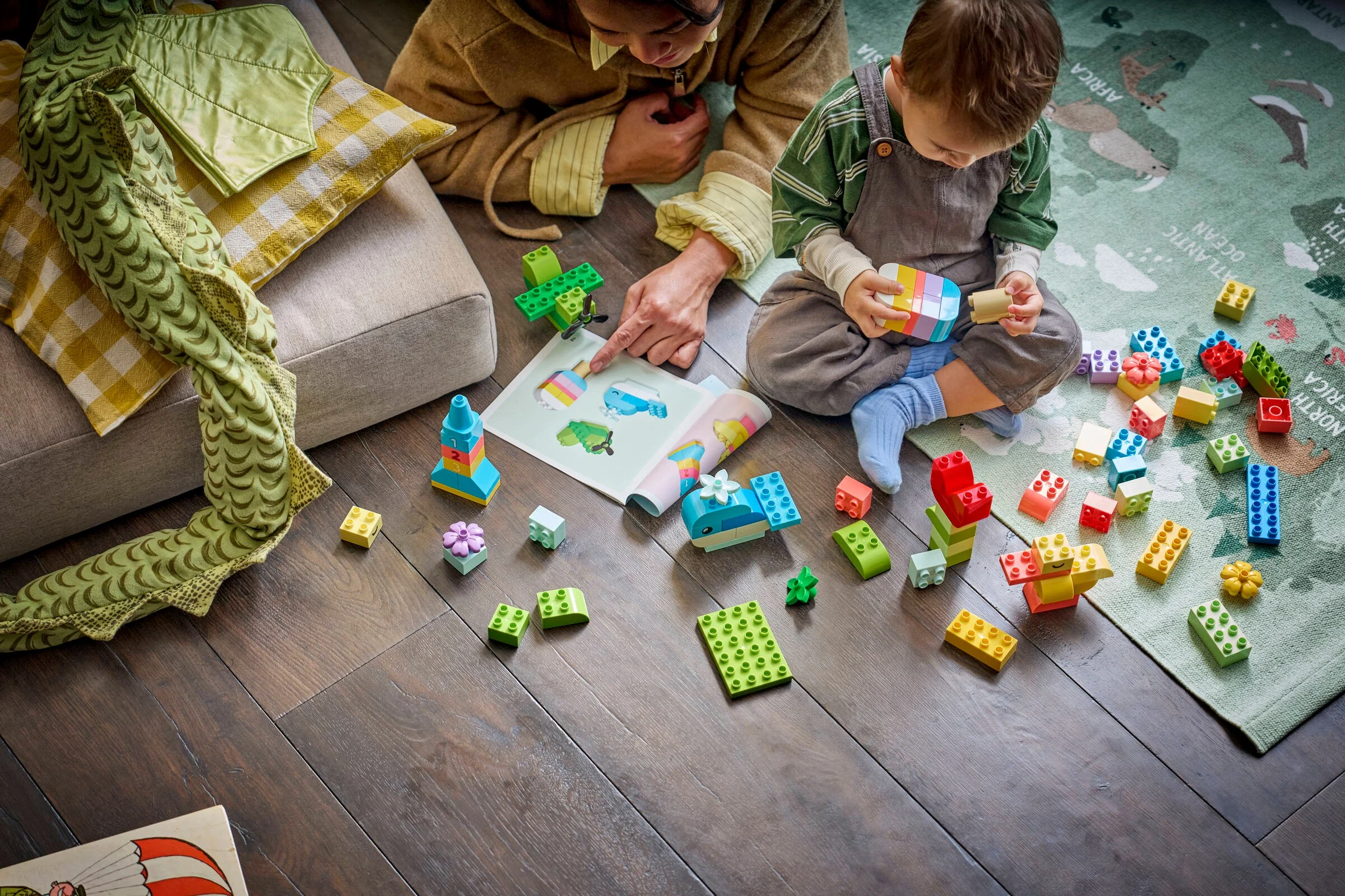 Copil și adult construind cu piese DUPLO colorate, urmând un ghid ilustrativ.