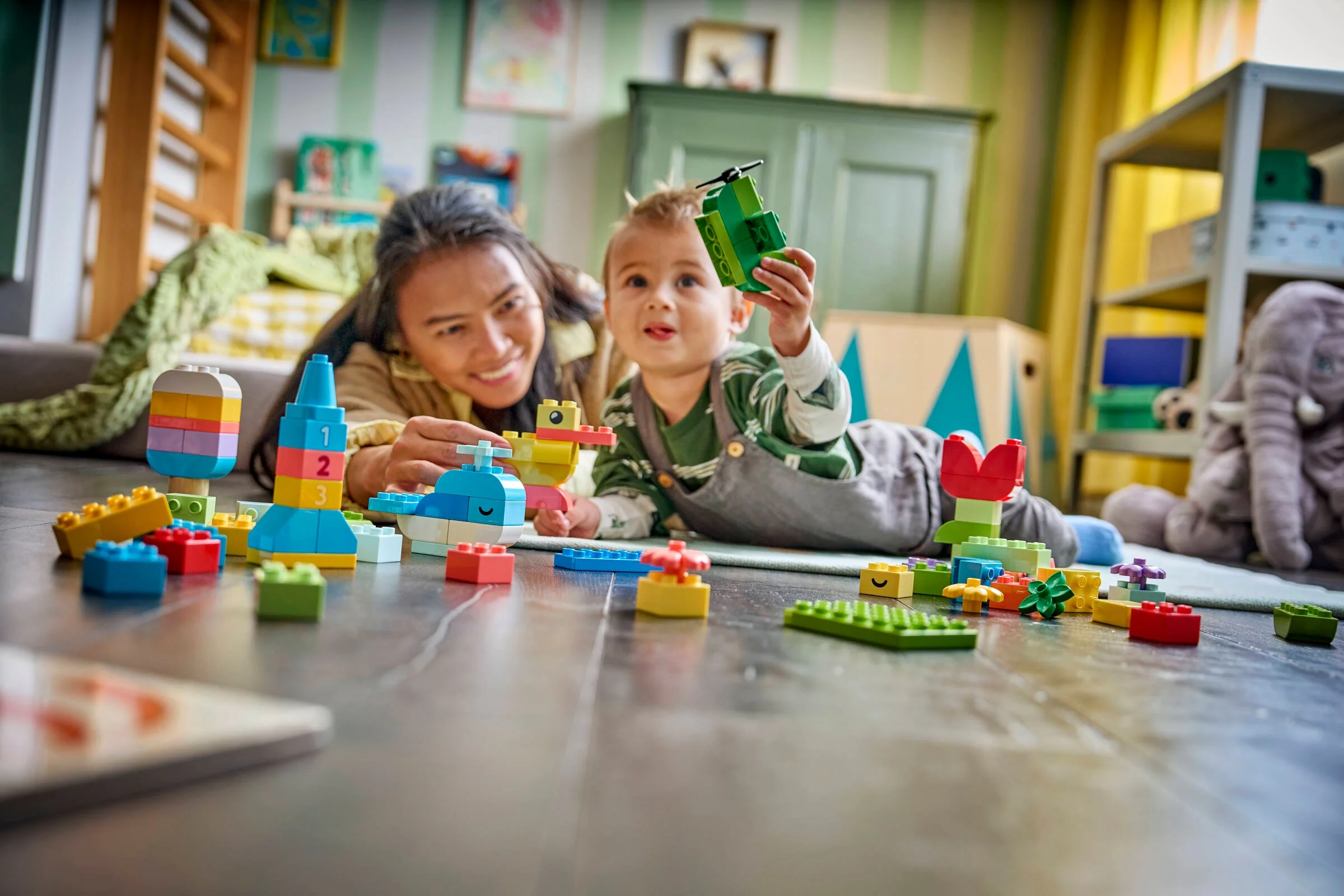 Mama și copil construind împreună cu cărămizi DUPLO colorate. Momente de joacă și creativitate.