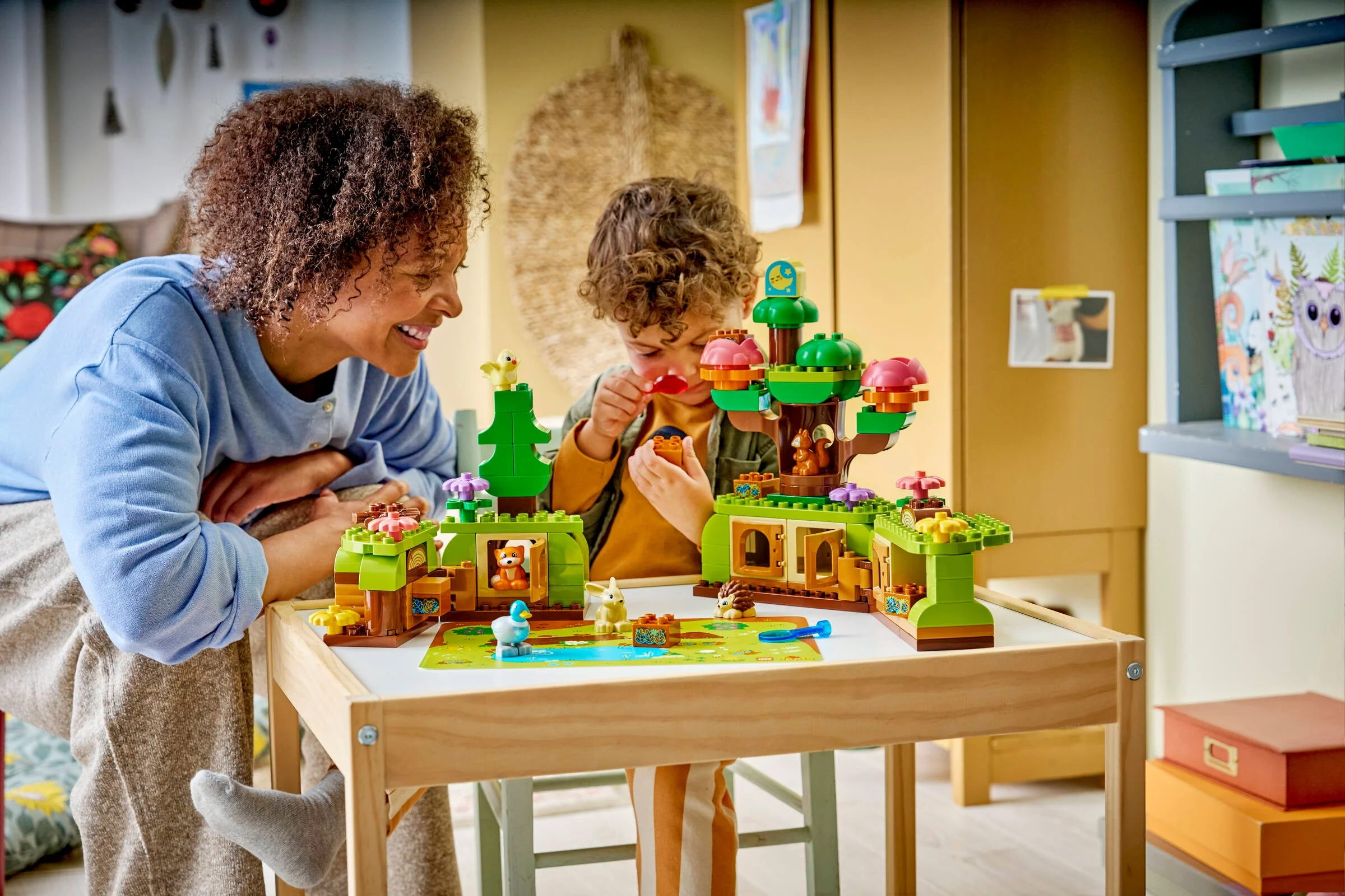Copil și adult se joacă împreună cu setul LEGO DUPLO Pădurea cu animale sălbatice.