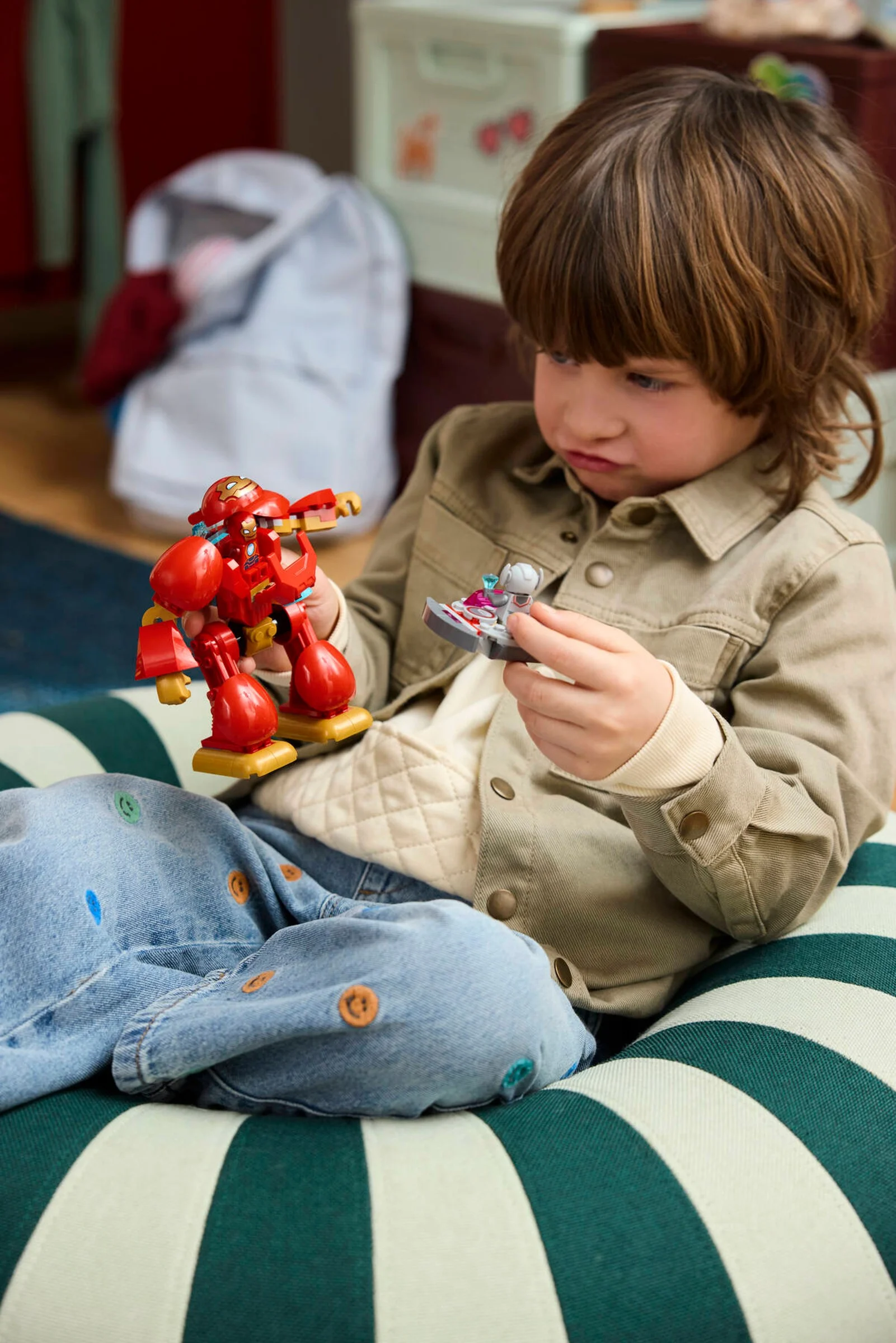 Un copil se joacă cu setul LEGO Ultron contra Iron Man, atent și concentrat.