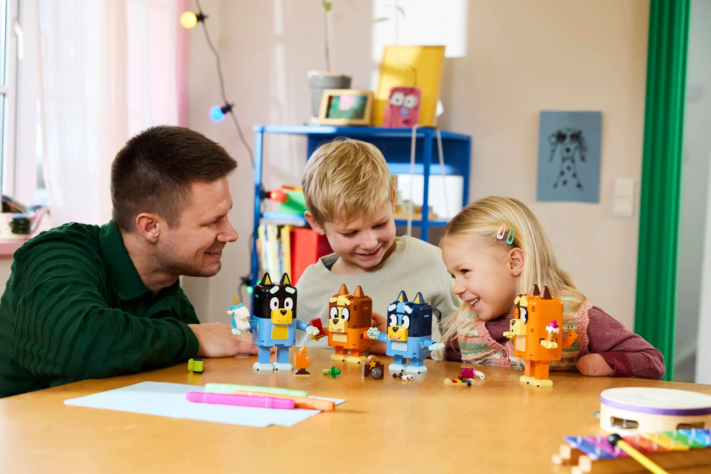 Familie construind personajele Bluey din cărămizi LEGO. Distracție creativă pentru copii.
