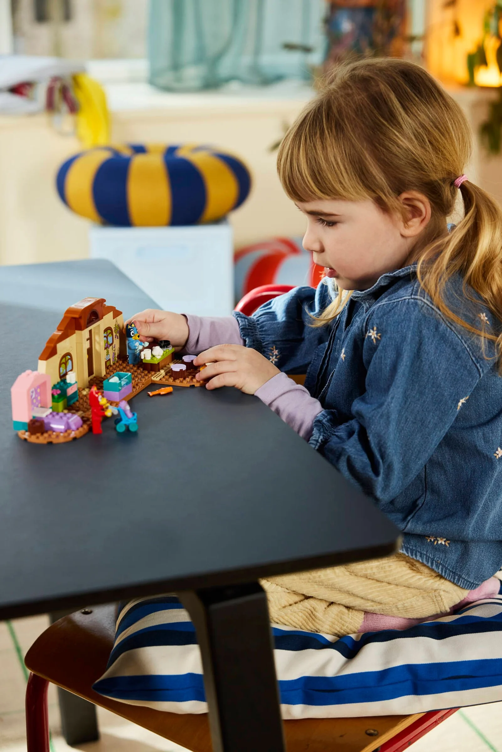 O fetiță se joacă cu setul LEGO Bluey: Școala. Setul include figurine și elemente de recuzită.