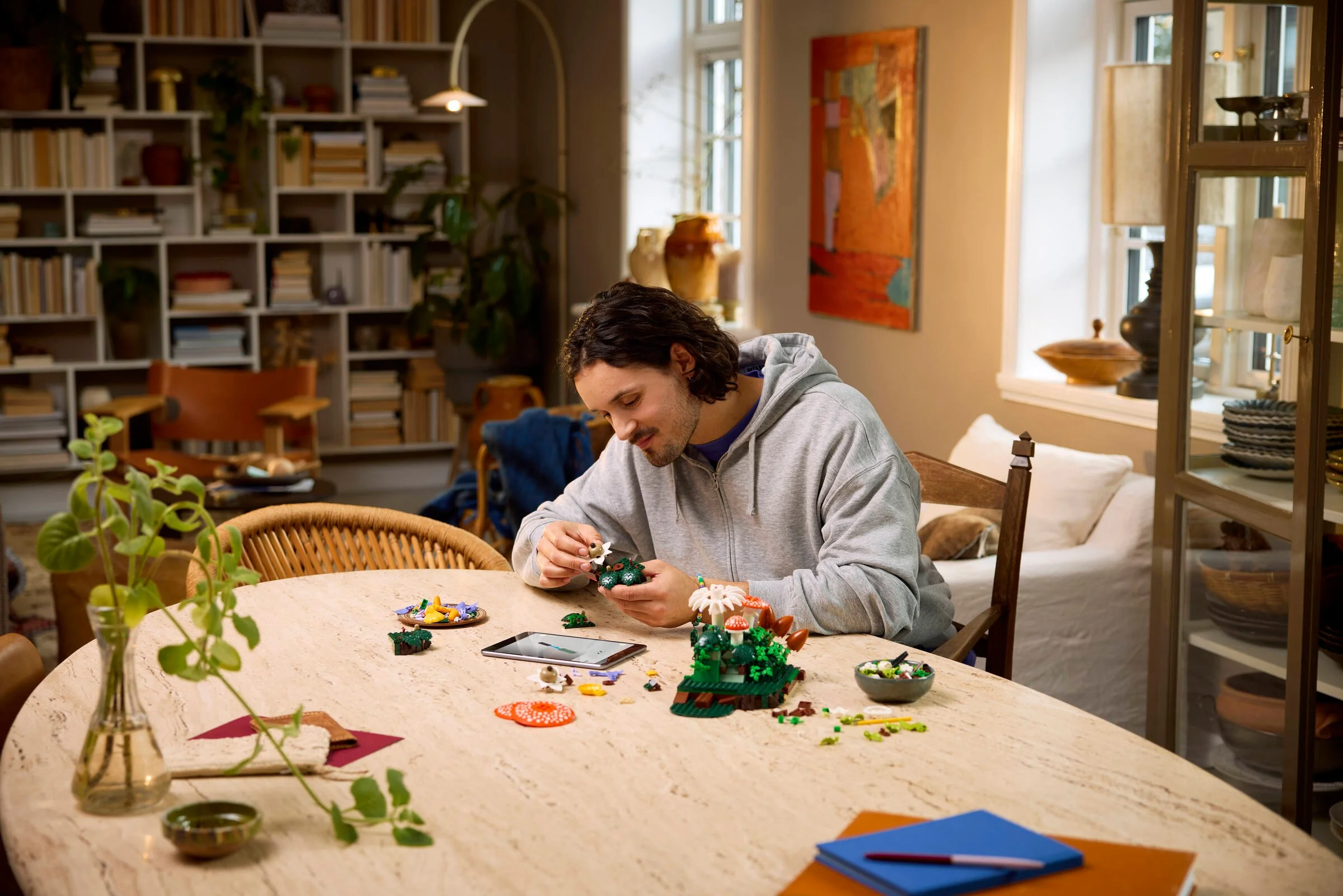 Bărbat construind setul LEGO 11505 Ciuperci din Pădure acasă. Asamblare relaxantă, decor natural.
