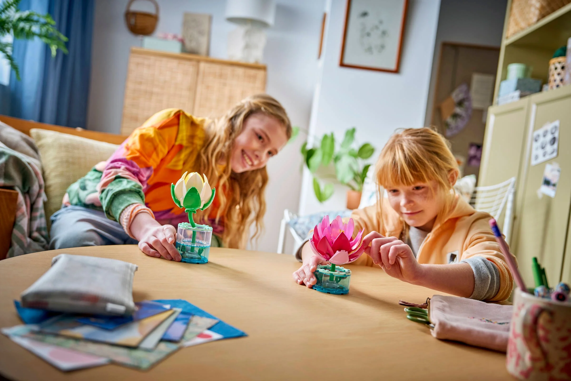 Două fete asamblează setul LEGO Water Lilies 11511. Construiesc nuferi colorați, creând un decor frumos.